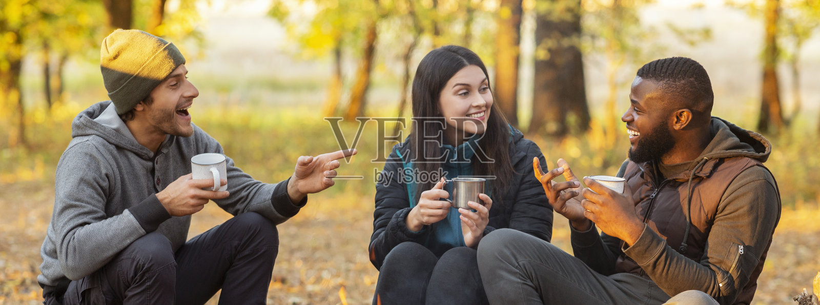 一群快乐的朋友在秋天的树林里野餐照片摄影图片
