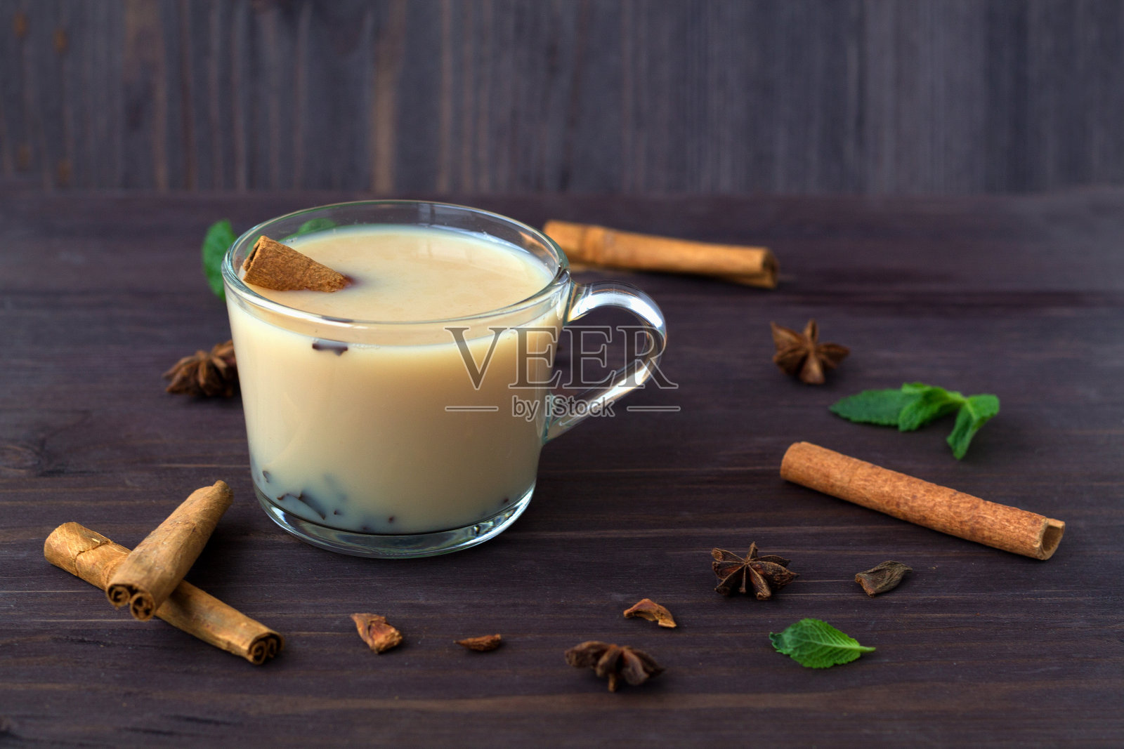 一杯牛奶和香料的茶在木制的黑色背景上。香料:茴香、肉桂、薄荷。圣诞装饰。健康的生活方式。玛莎拉茶照片摄影图片