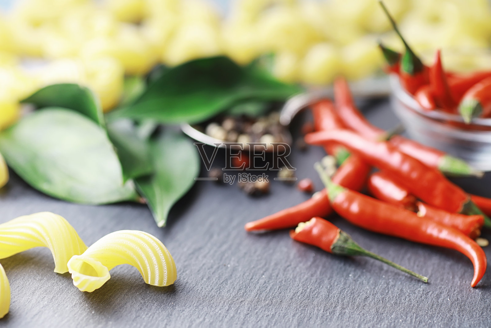 石头背景上的生意大利面。加上调味料和香料,还有辛辣的辣椒。照片摄影图片