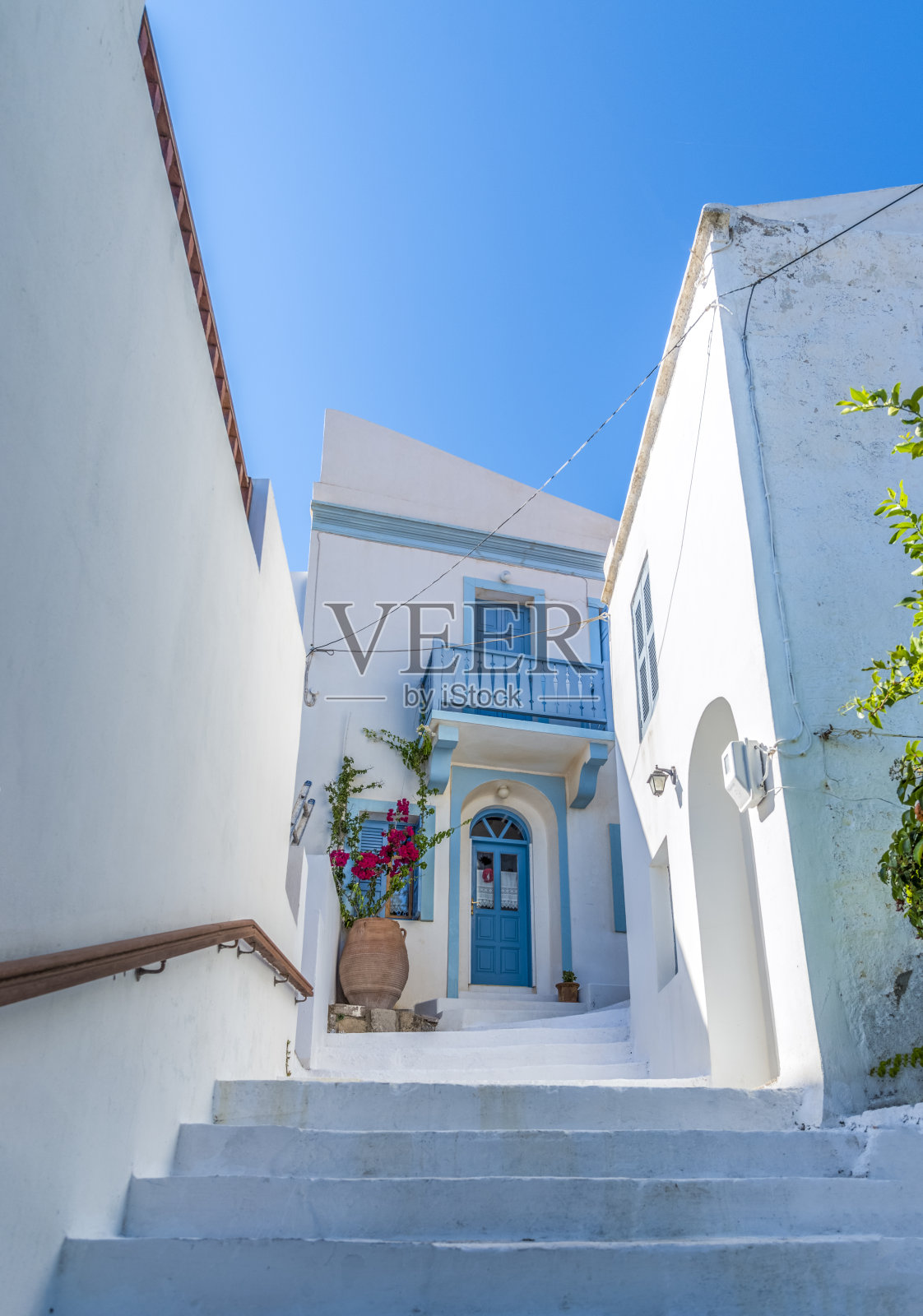 典型的基克拉迪(cycladic)式的、刷成白色、开着五颜六色花朵的小巷照片摄影图片