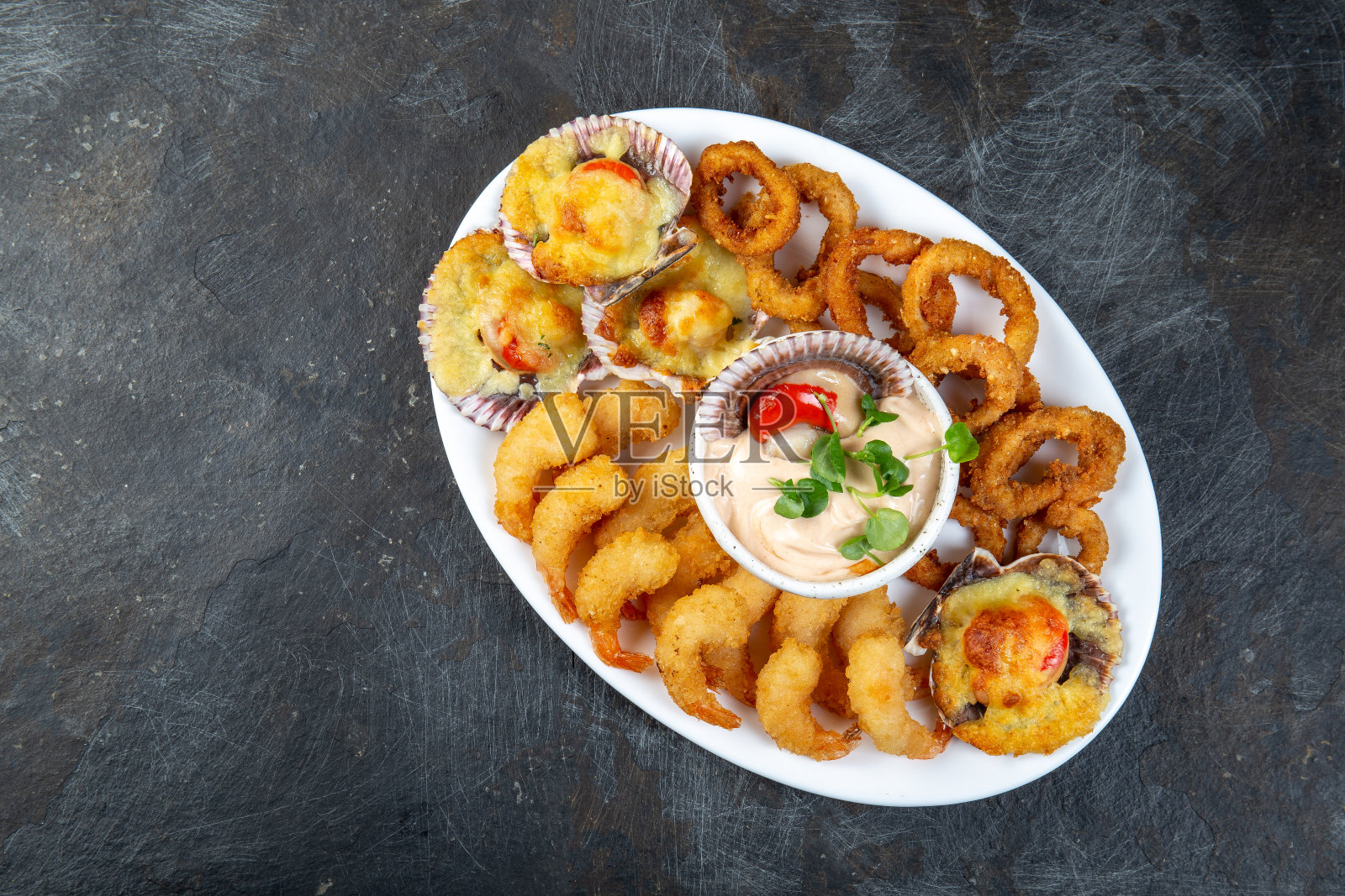 秘鲁的食物。Piqueo热。热海鲜盘炒虾仁,鱿鱼圈和烤扇贝配酱汁照片摄影图片