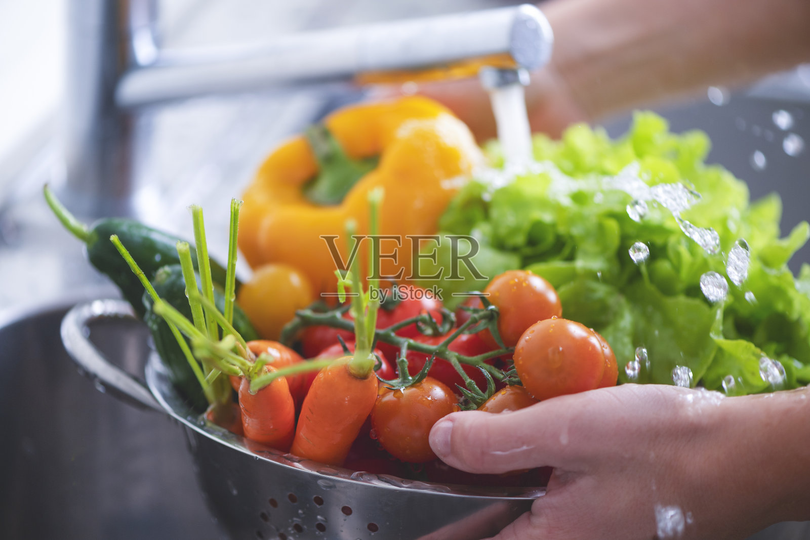 在水槽里洗各种蔬菜的女人。照片摄影图片