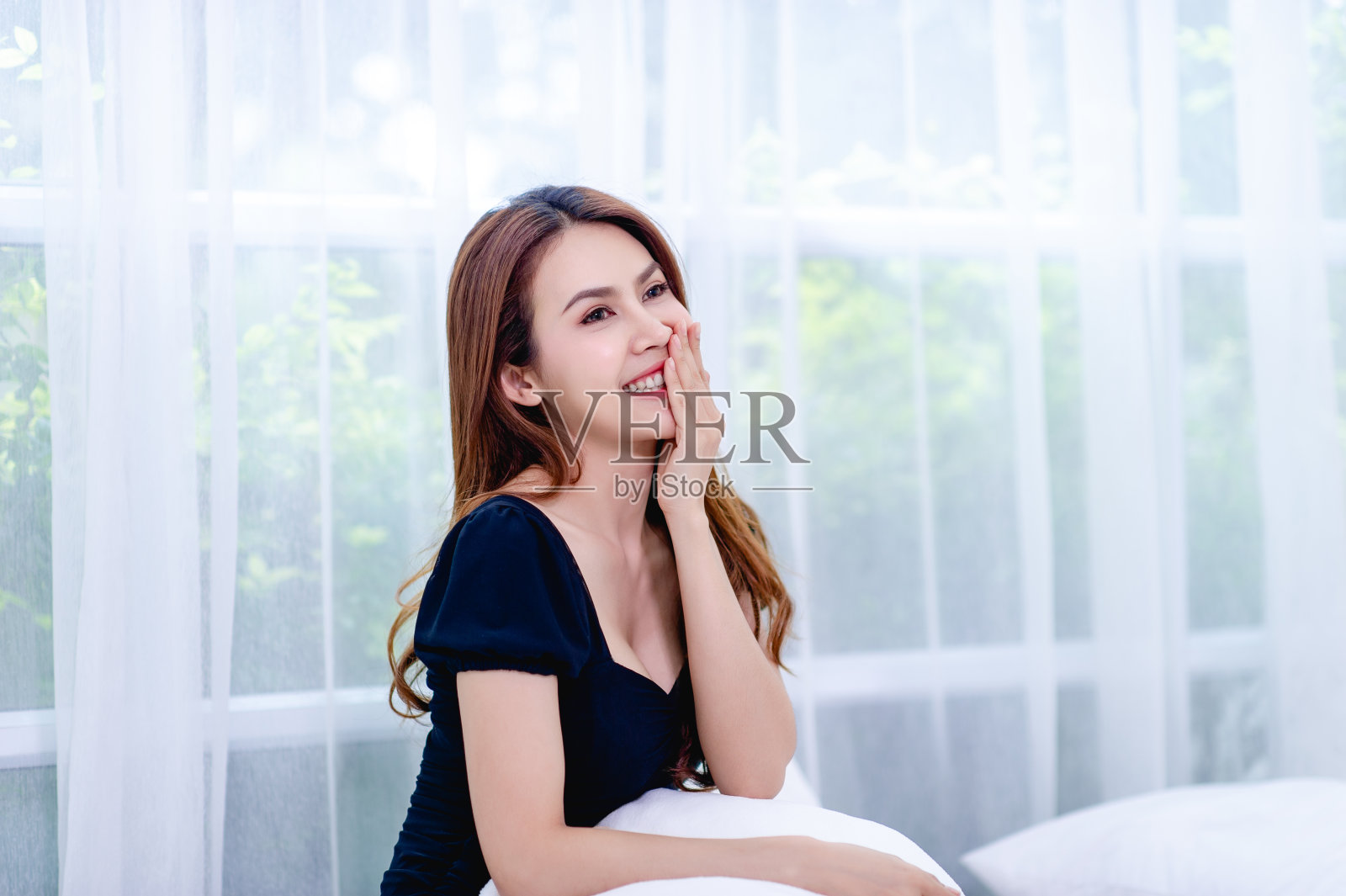 一个女人在白色的卧室里快乐的微笑过幸福生活的概念照片摄影图片