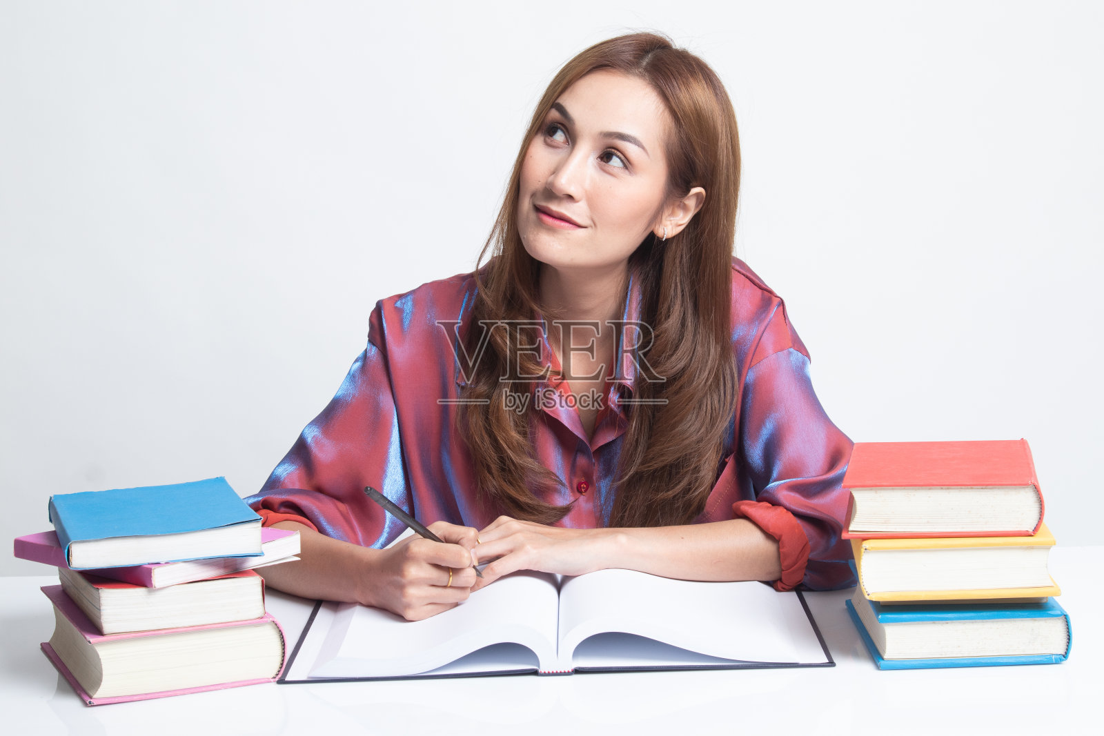 一位年轻的亚洲妇女在桌子上看书。照片摄影图片