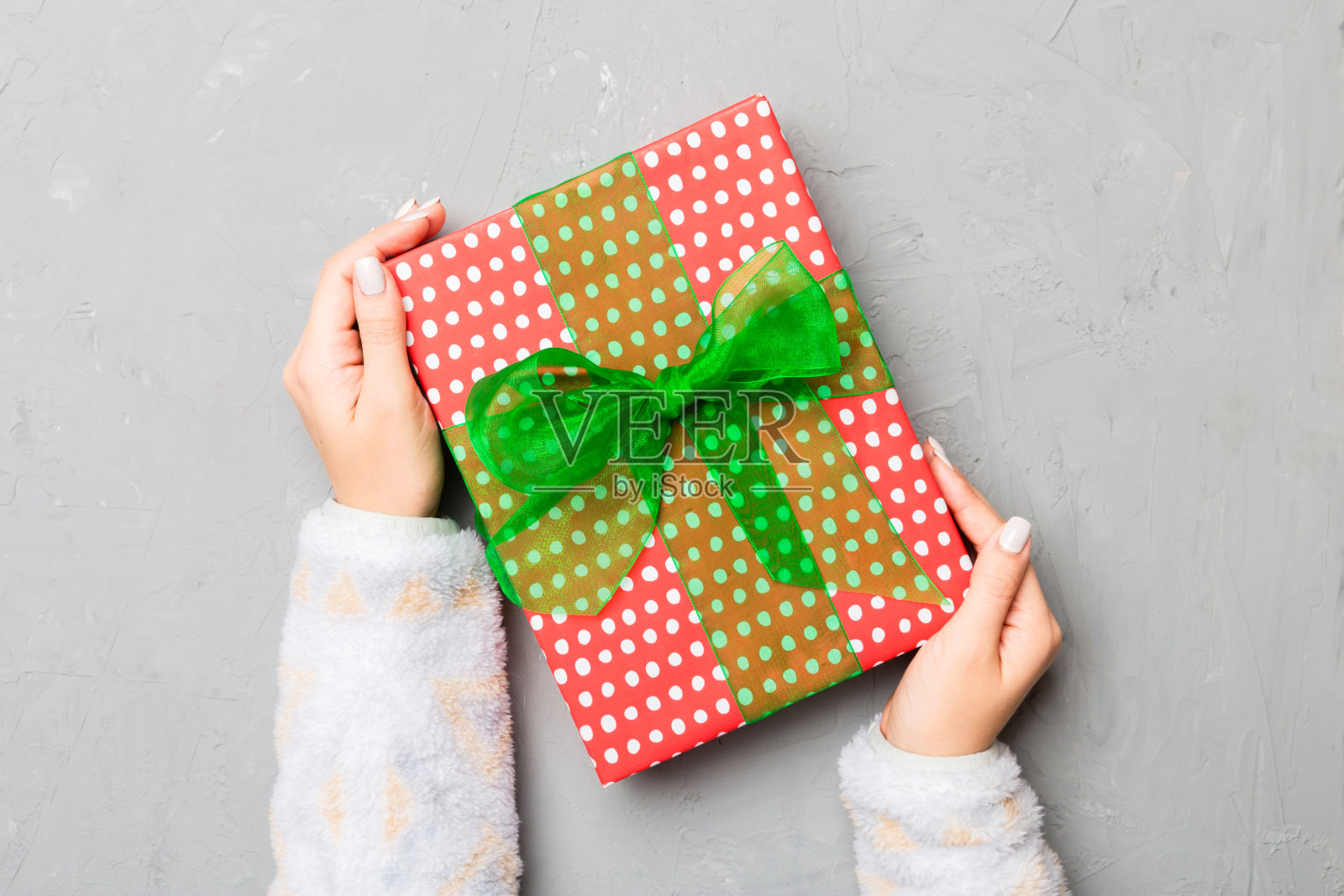 灰色水泥背景上,女性双手紧握。圣诞节或其他节日的节日背景。平铺样式顶视图与复制空间照片摄影图片