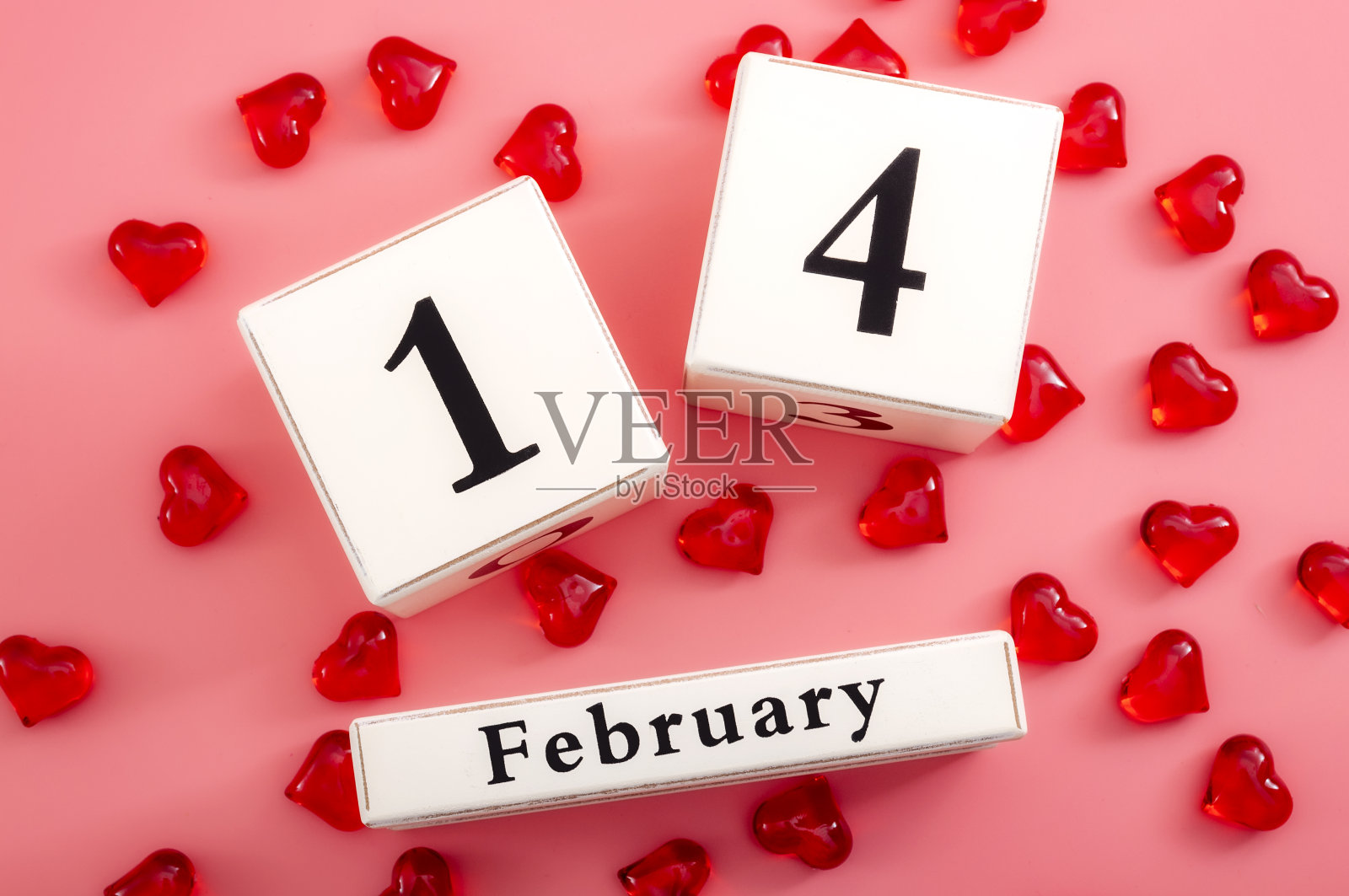 情人节和庆祝爱情概念主题与近距离块日历显示2月14日旁边的红色心与每个心指向不同的方向孤立在粉红色的背景照片摄影图片