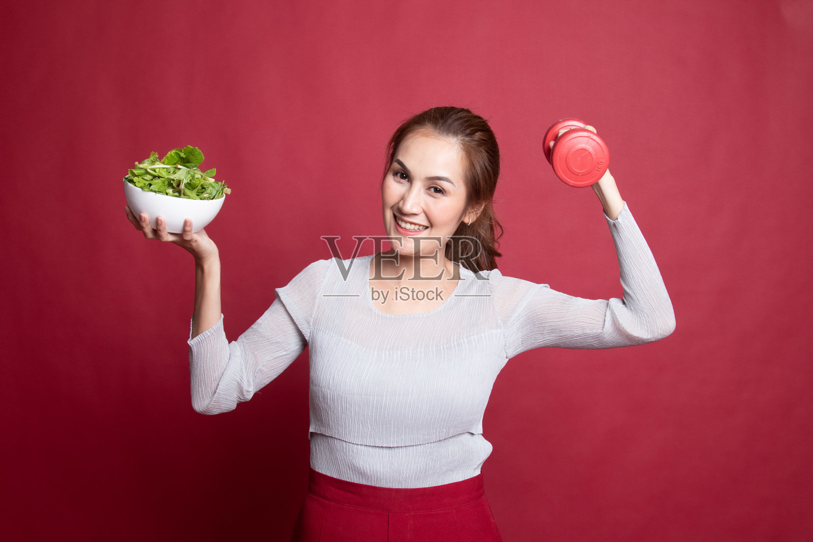 健康的亚洲女人,拿着哑铃和沙拉。照片摄影图片