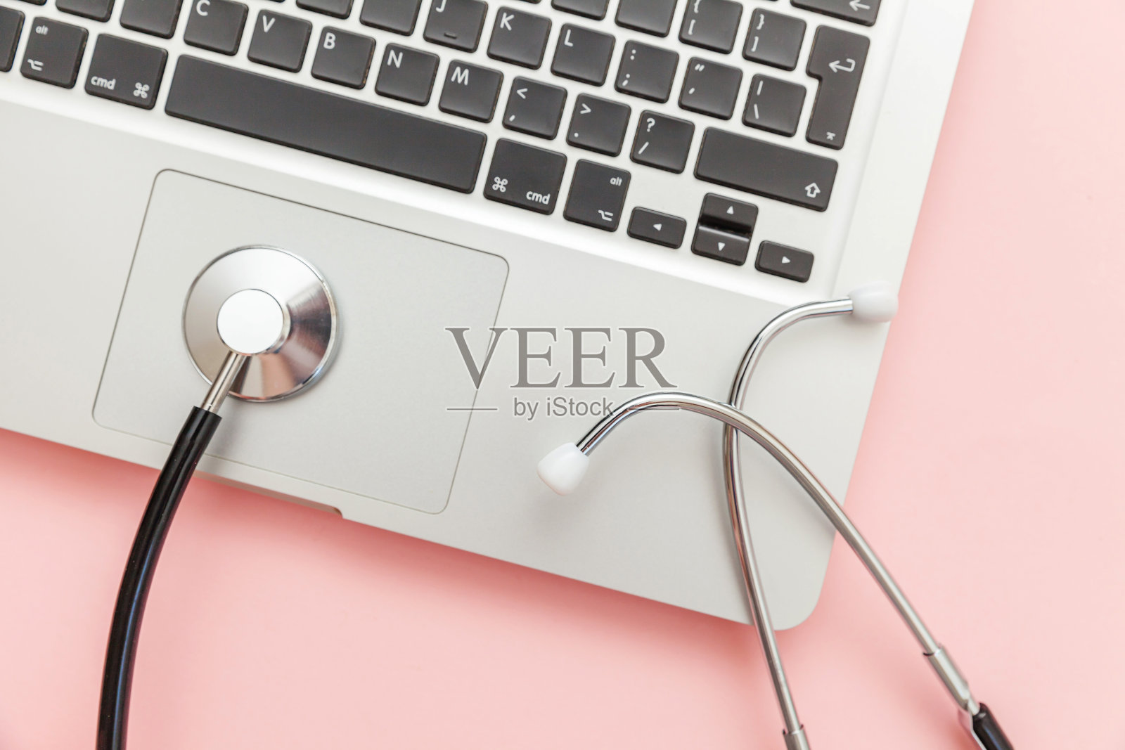 听诊器键盘笔记本电脑隔离在粉红色的背景。现代医学信息技术和软件推动了概念的发展。计算机和小部件的诊断和修理照片摄影图片