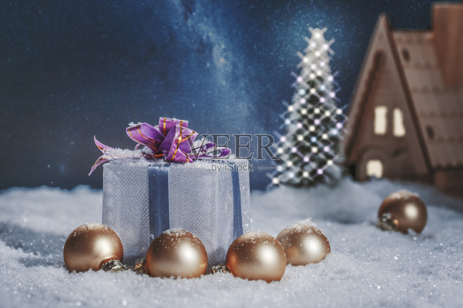 圣诞静物,礼盒带着蝴蝶结在下雪的房子附近和圣诞树上过夜。照片摄影图片