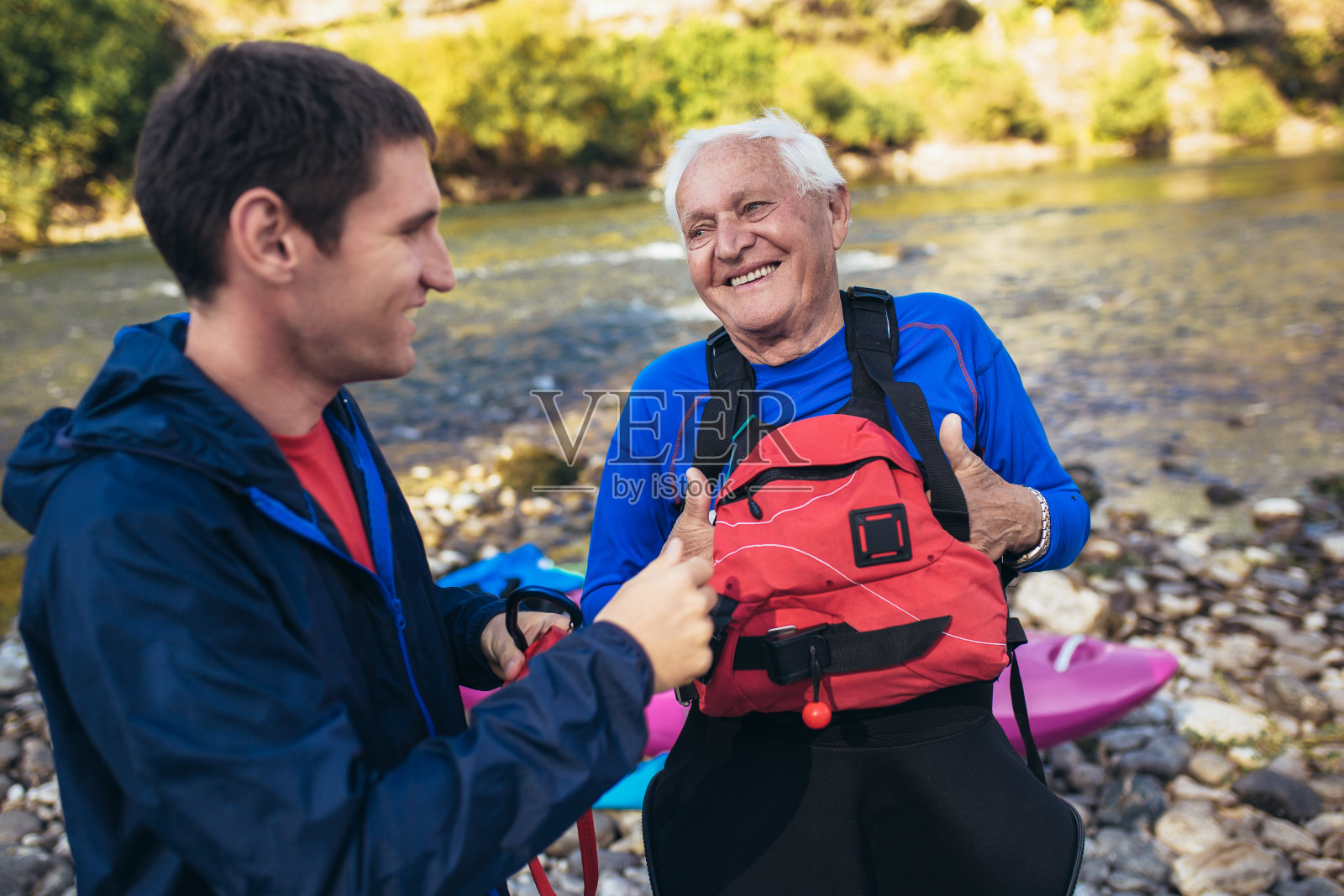 老人准备在山间河流上划独木舟。照片摄影图片