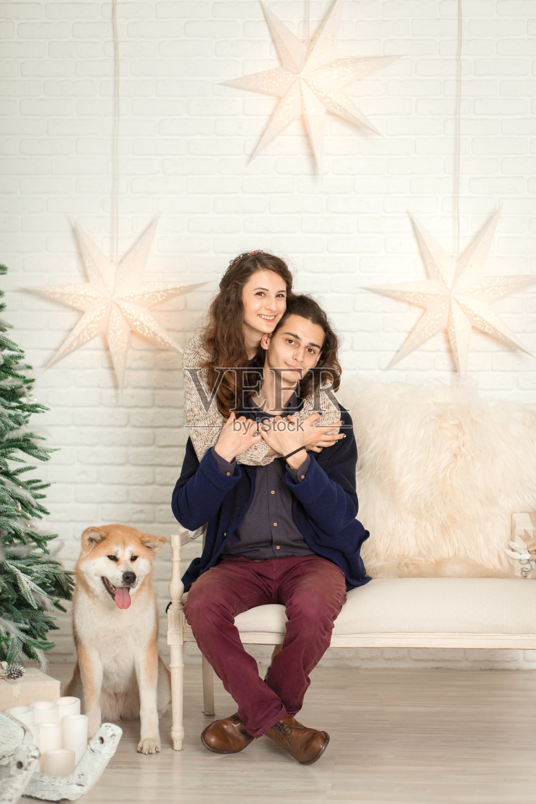 圣诞装饰品。一对年轻幸福的情侣坐在长椅上拥抱亲吻,旁边是一只狗照片摄影图片