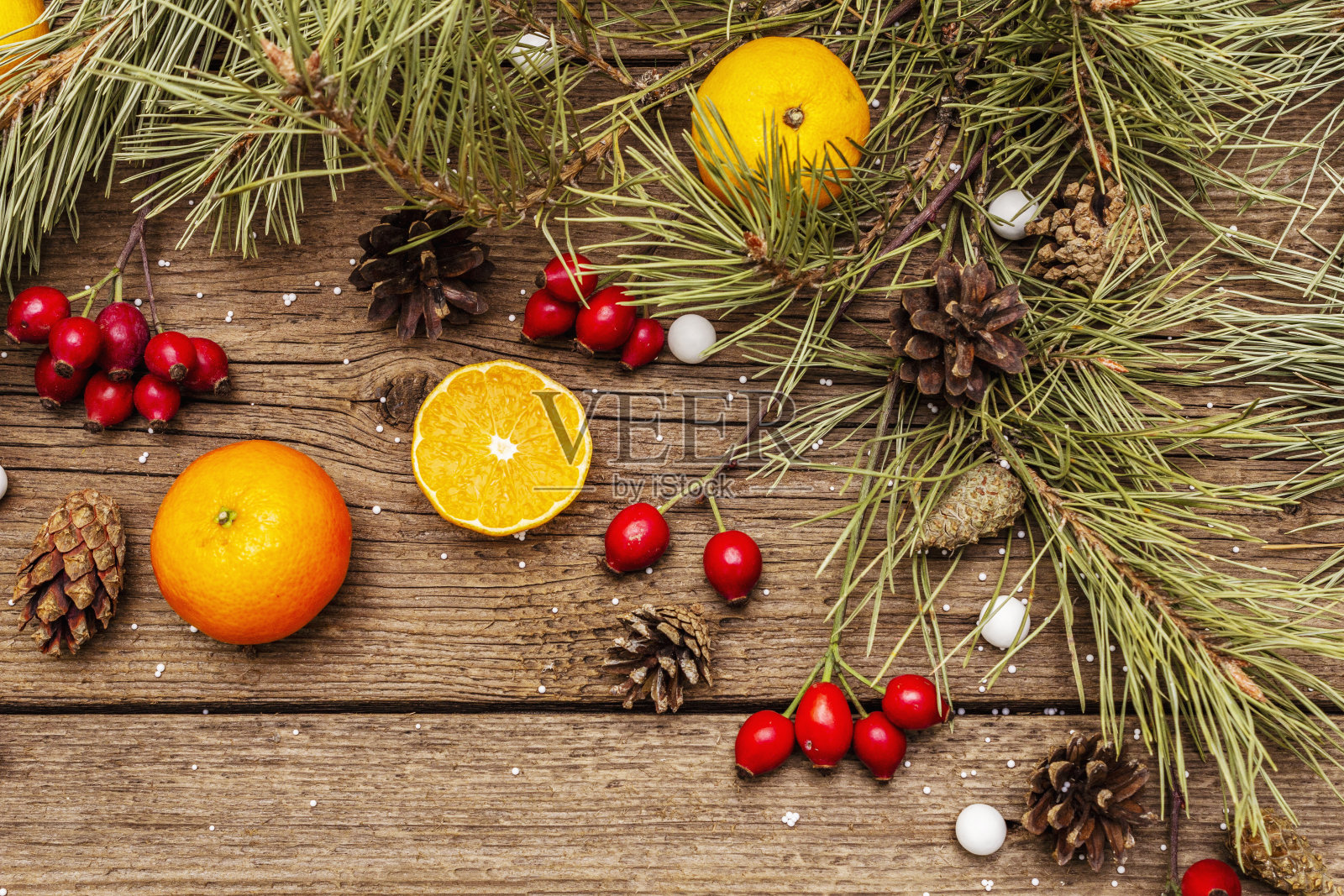 圣诞节的精神背景。新鲜橘子,玫瑰果,糖果,松枝和松果,人造雪。自然装饰,老式木板照片摄影图片