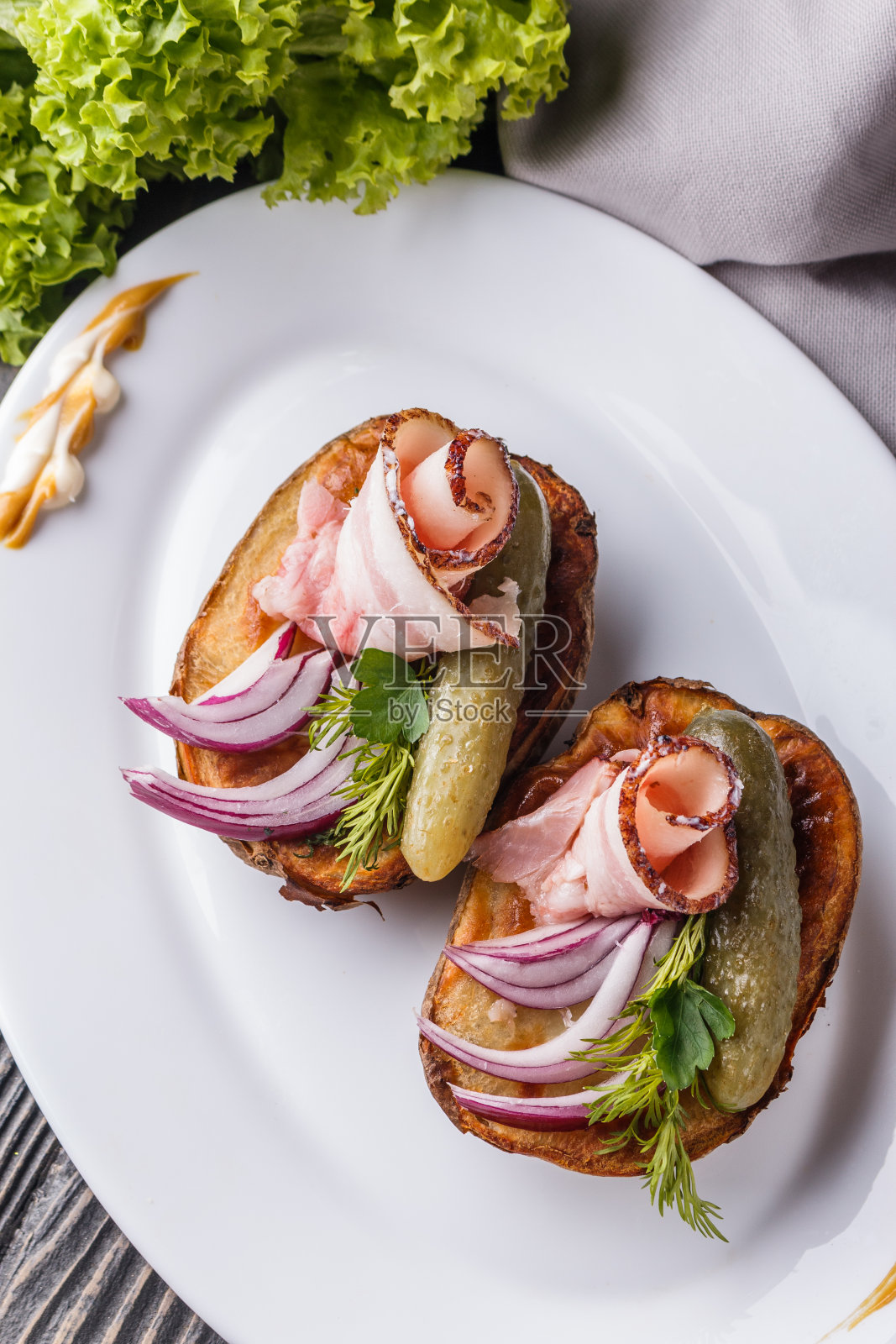 半块烤土豆,配腌黄瓜、莳萝、沙罗和洋葱放在木桌上照片摄影图片