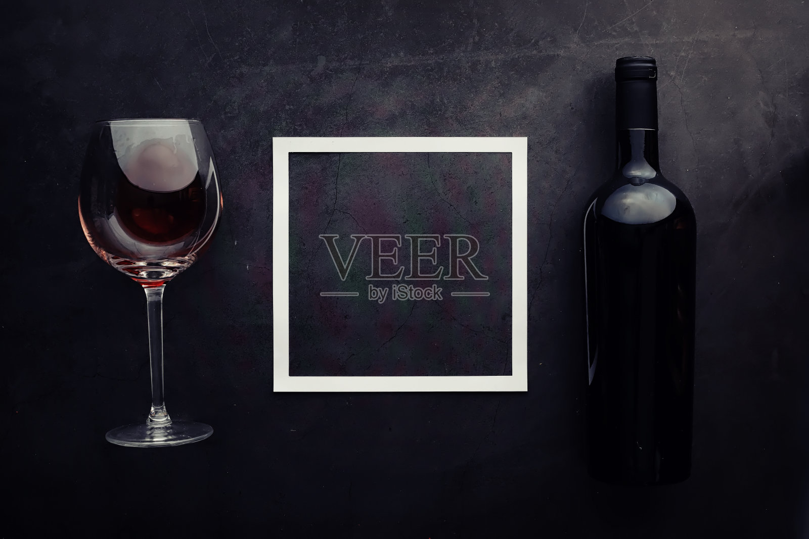 酒杯和黑酒瓶。坚果,奶酪和西红柿作为零食。照片摄影图片