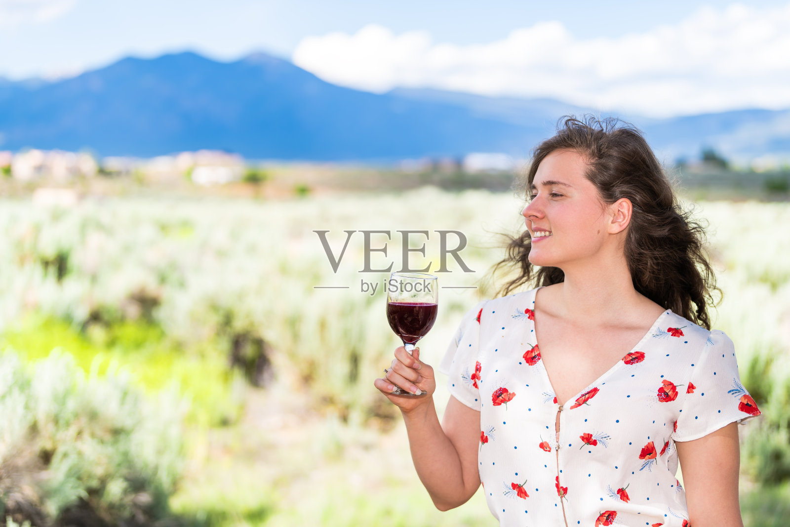 女人品尝红酒从Taos Sangre de Cristo山从Ranchos de Taos山谷背景后院葡萄园照片摄影图片