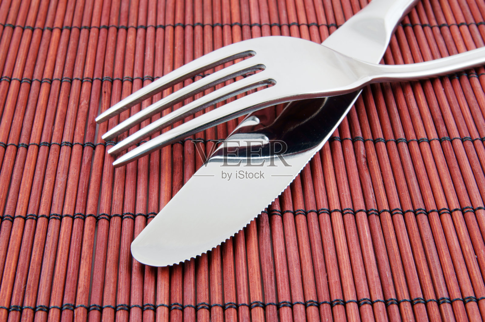 近距离的刀和叉在红竹席上照片摄影图片