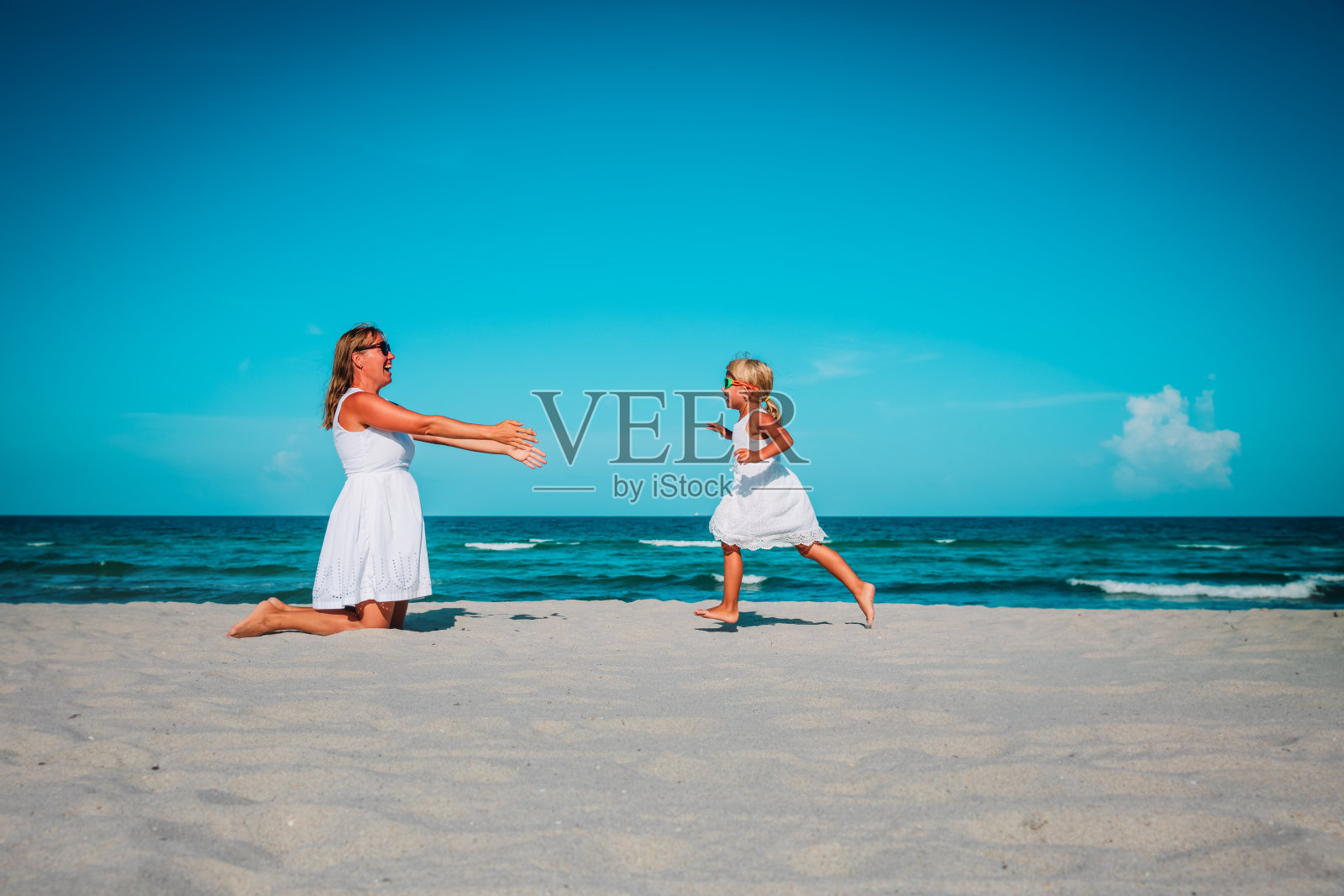 快乐的妈妈和小女儿在沙滩上玩耍,家人照顾照片摄影图片