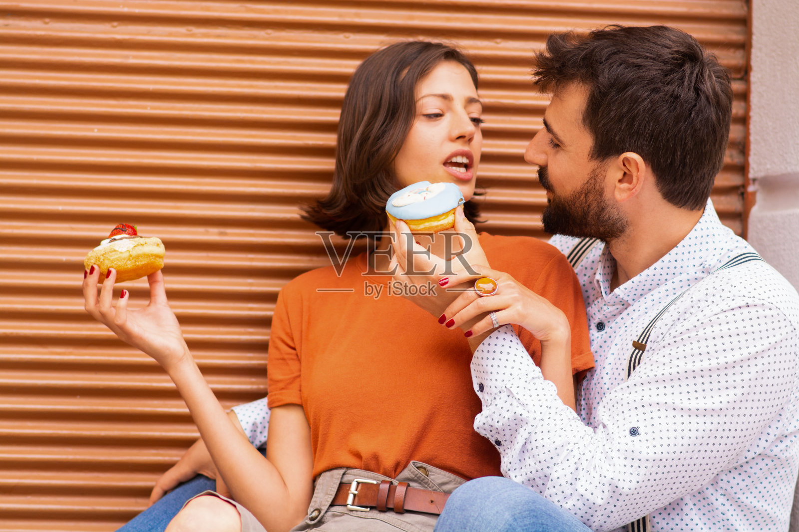 一对夫妇在街上吃甜甜圈。照片摄影图片