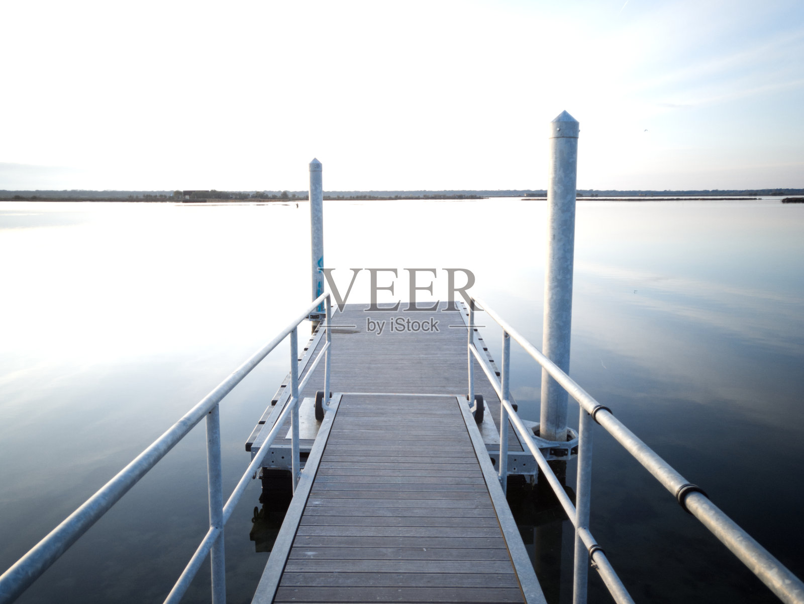 日落时分在泻湖上的钢码头。照片摄影图片