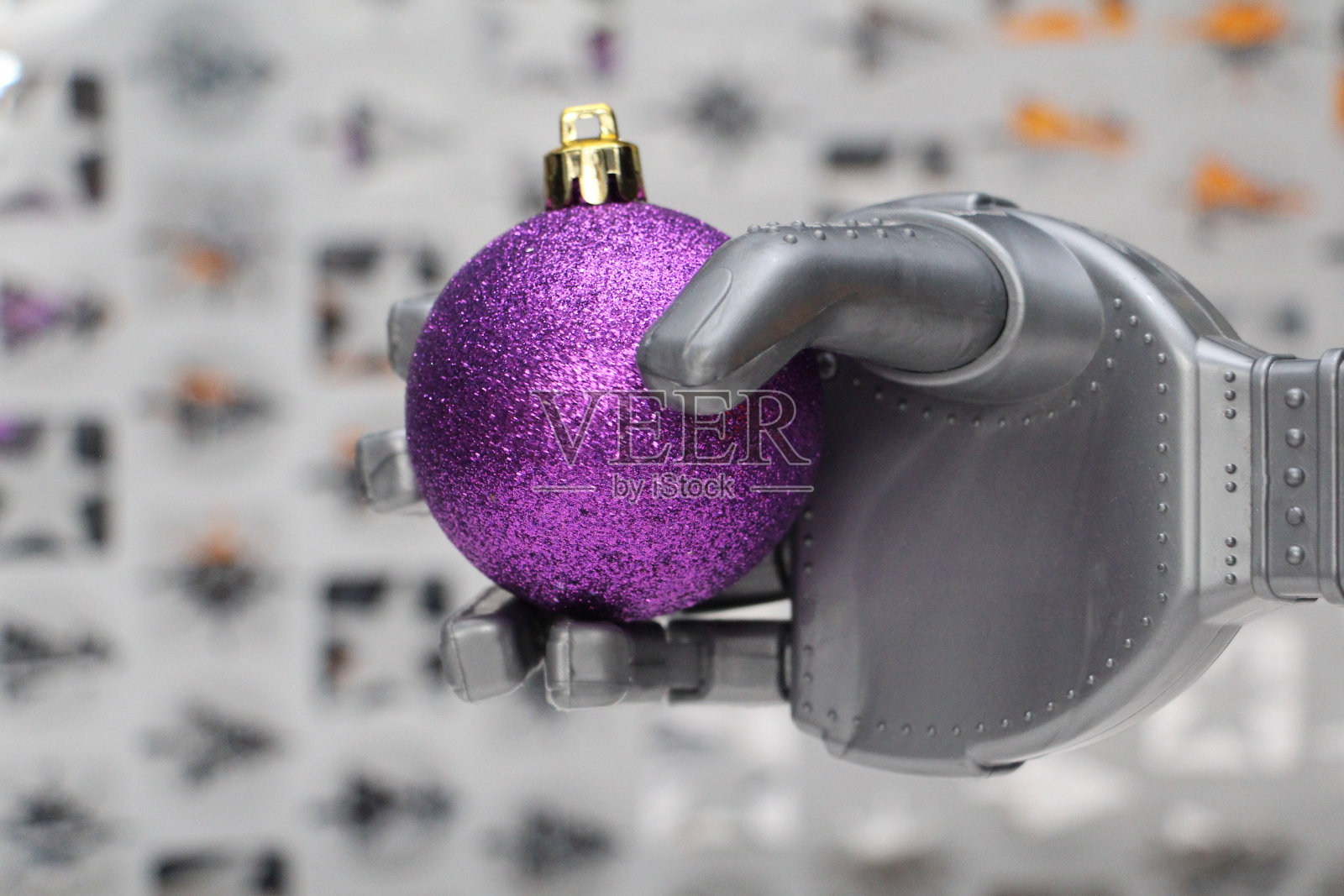 一个机器人手里拿着一个紫色的圣诞树装饰品。照片摄影图片