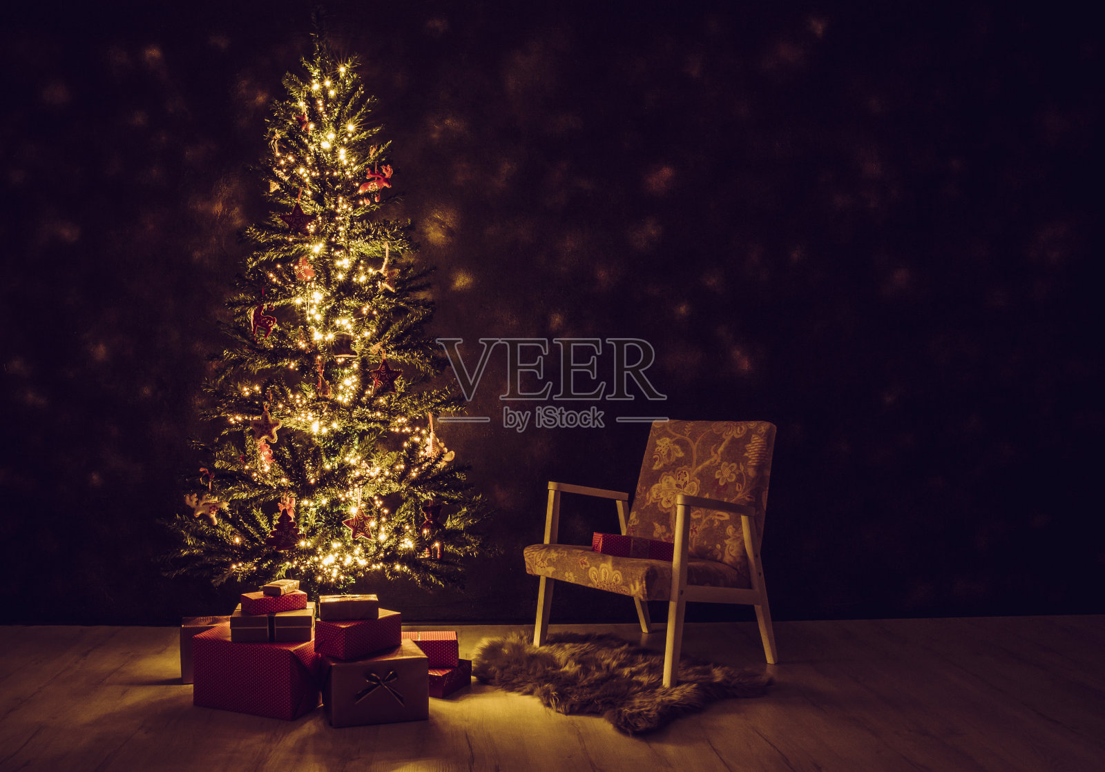 装饰魔法圣诞树前的黑墙用圣诞红纸包裹的礼物树下,复古的椅子旁边。的夜晚。照片摄影图片