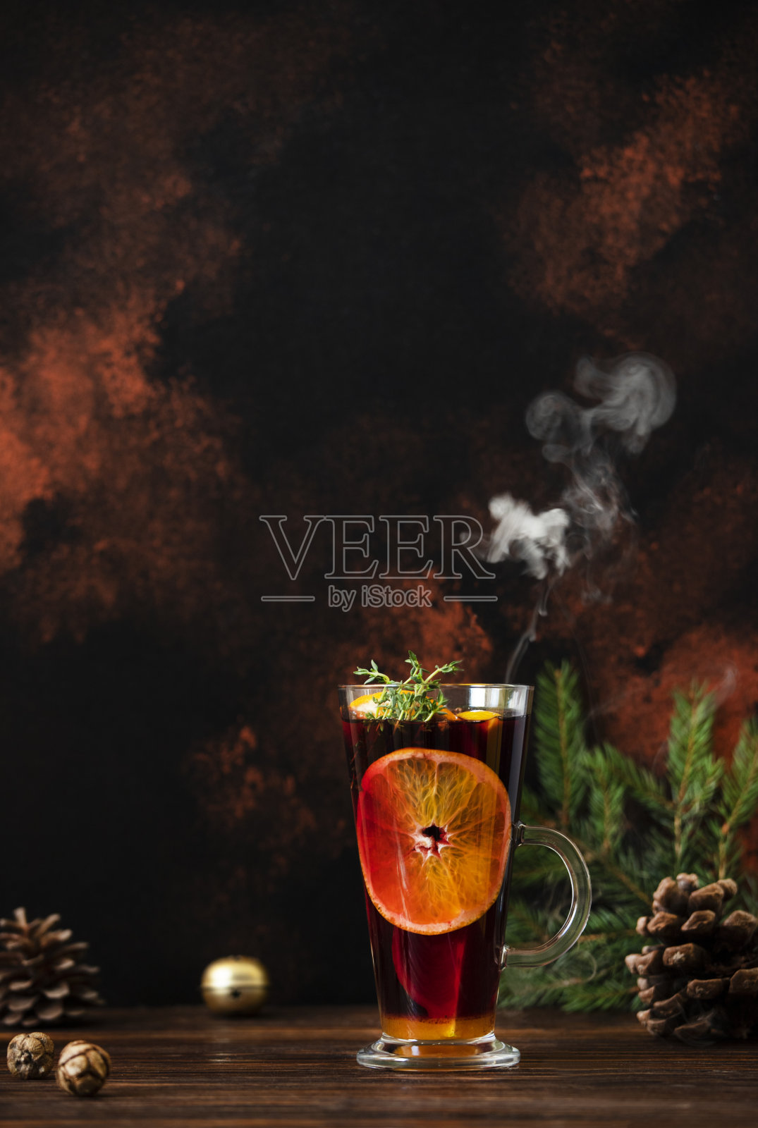 热红酒(mulmulwine)是一种用红酒、柑橘、水果和香料盛在装有圣诞装饰的木桌上的杯子里的热饮。黑暗的背景。特写,彩色,copyspace,垂直照片摄影图片