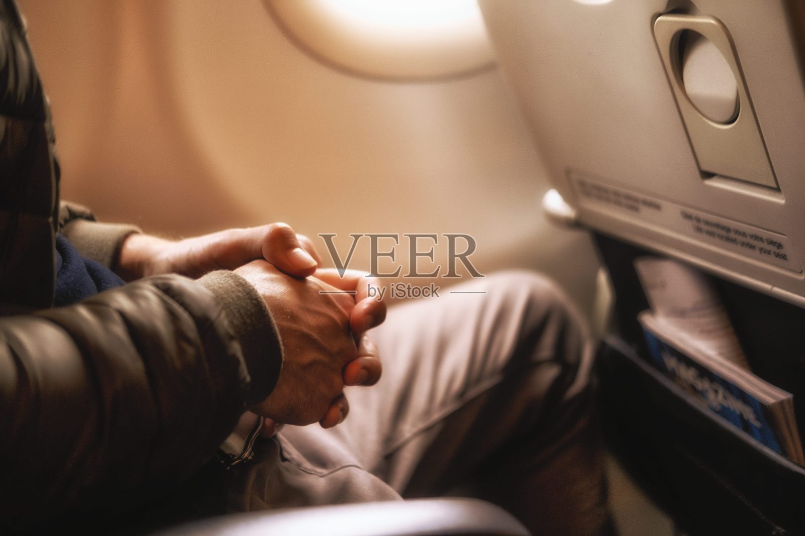 坐在飞机窗边的人把手拉近照片摄影图片