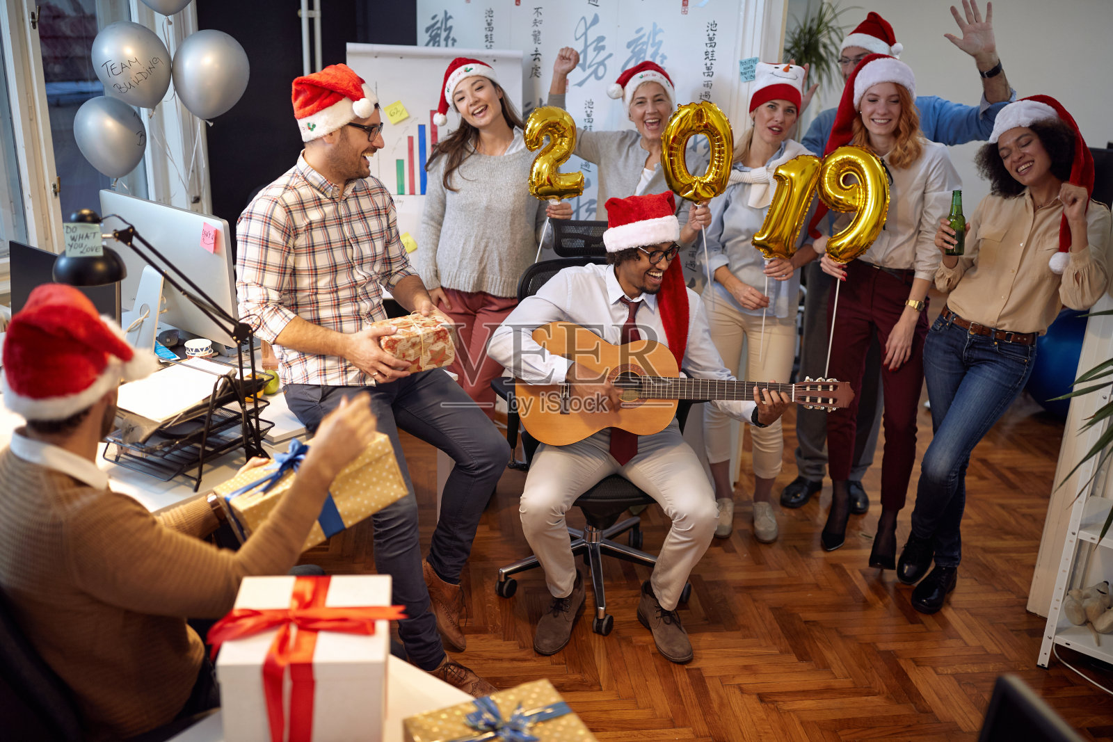 快乐的商业工作者在圣诞派对上一起在圣诞帽上跳舞照片摄影图片