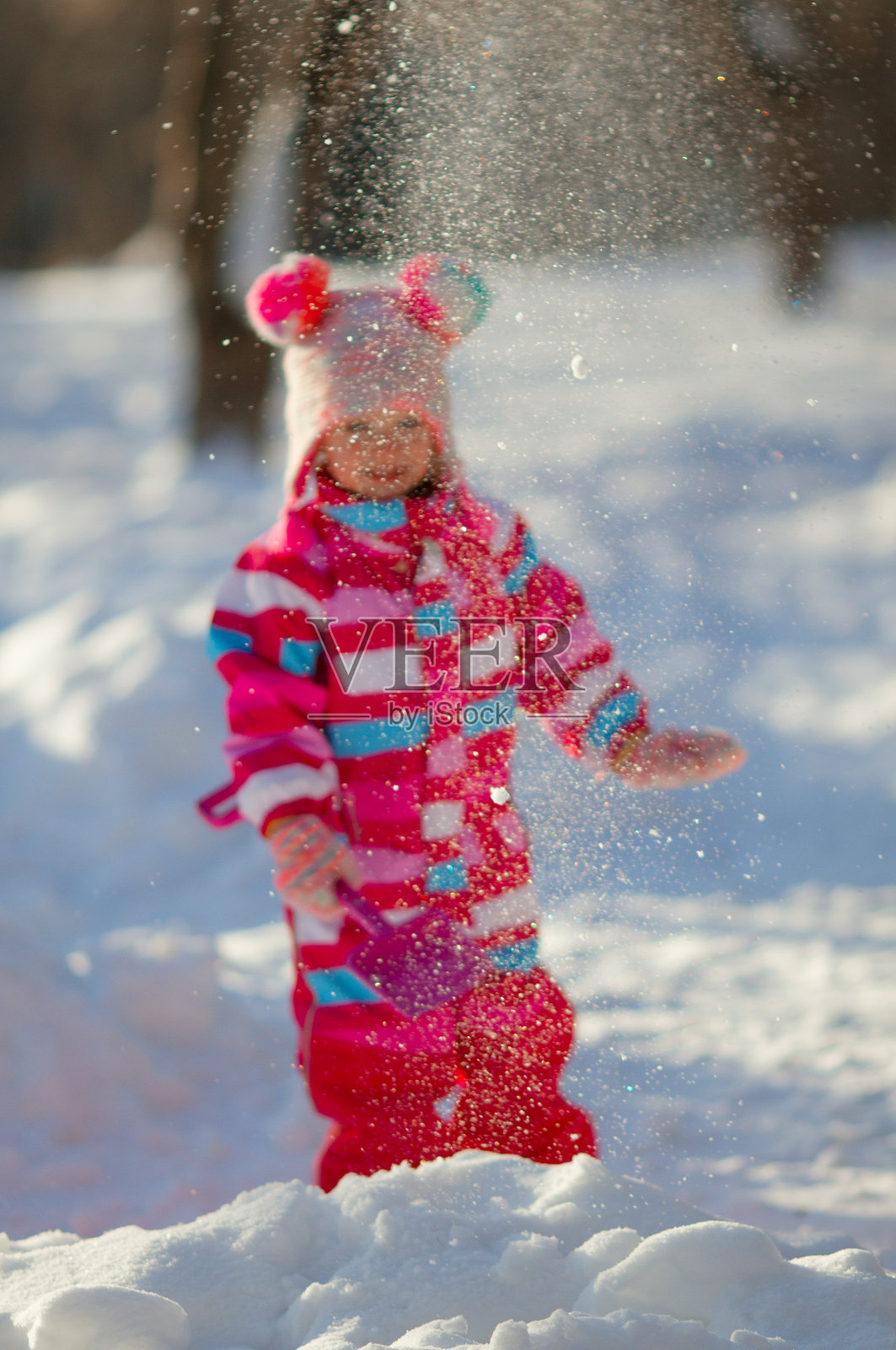 可爱的蹒跚学步的女孩穿着明亮的整体玩雪和铲子在冬天的一天照片摄影图片