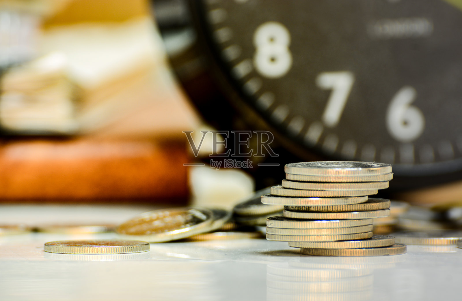 特写硬币堆叠与一个时钟。照片摄影图片