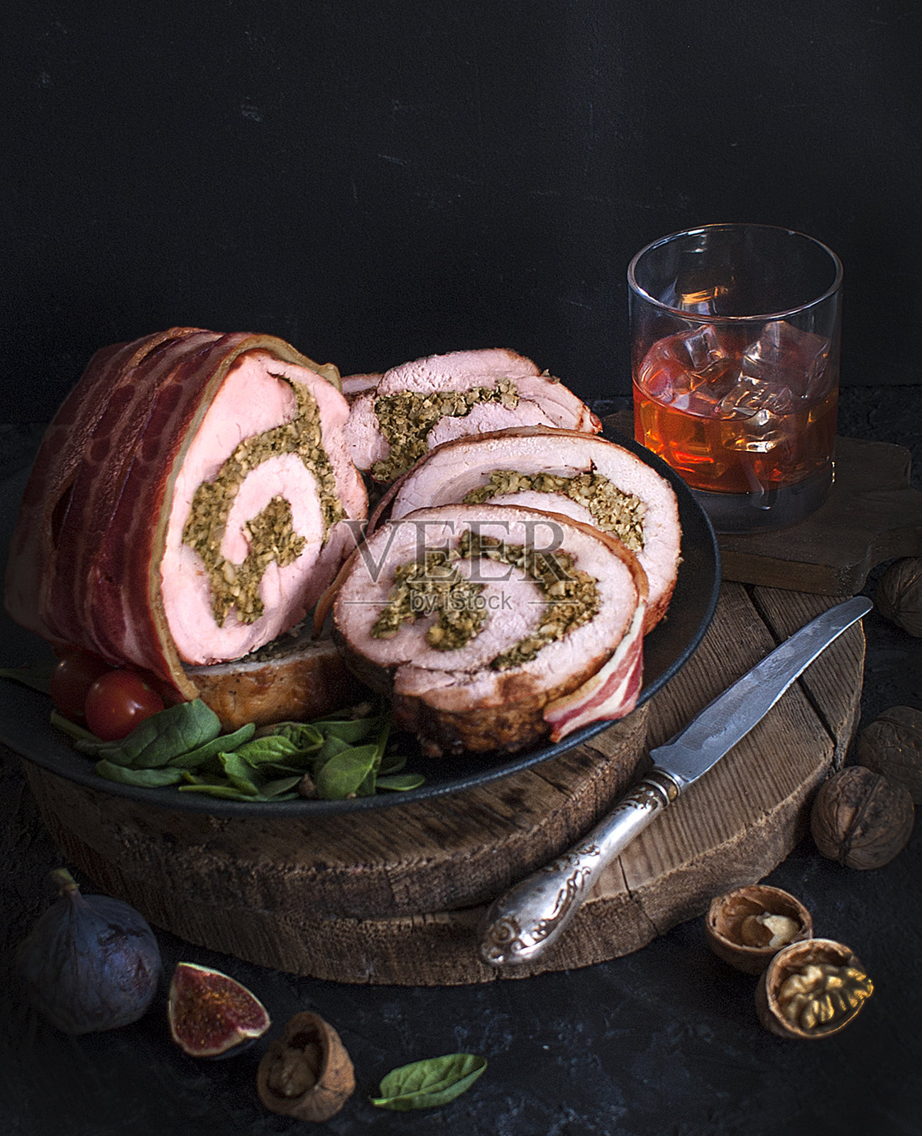 夹核桃和菠菜的猪肉火腿,再包上熏肉和一杯威士忌或白兰地。肉饼配坚果和香草。节日的美食。照片摄影图片