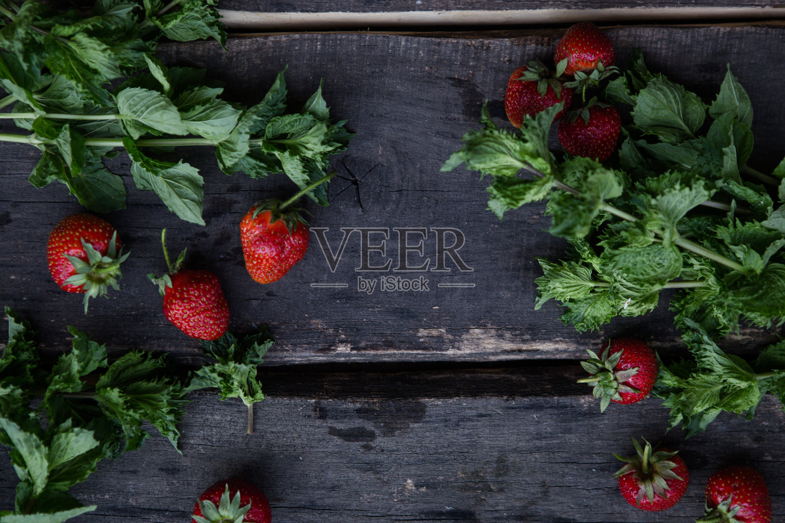 草莓切成两半,叶子放在木质背景上,配以薄荷照片摄影图片