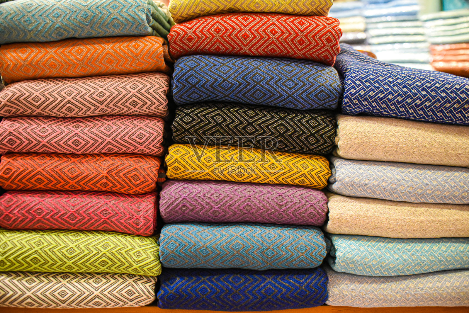 衣柜的架子上堆放着五颜六色的布料衣服照片摄影图片