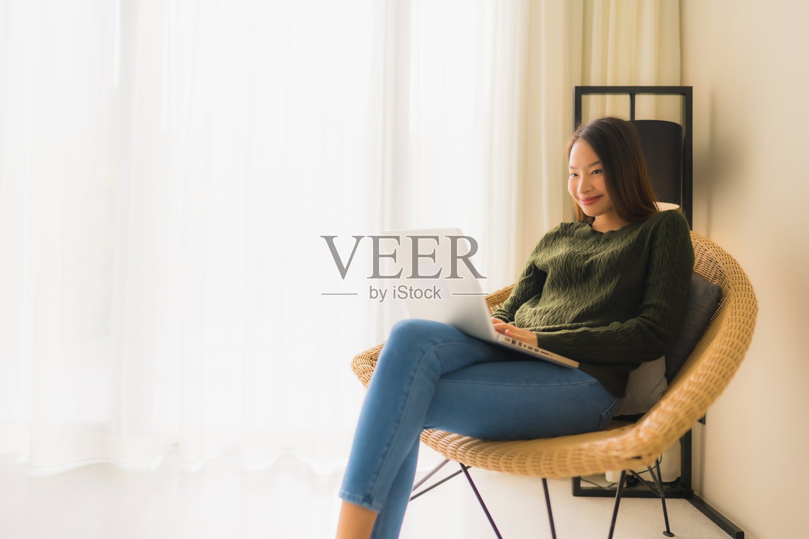 描绘美丽的年轻亚洲女性使用电脑或笔记本电脑工作或坐在沙发椅上照片摄影图片