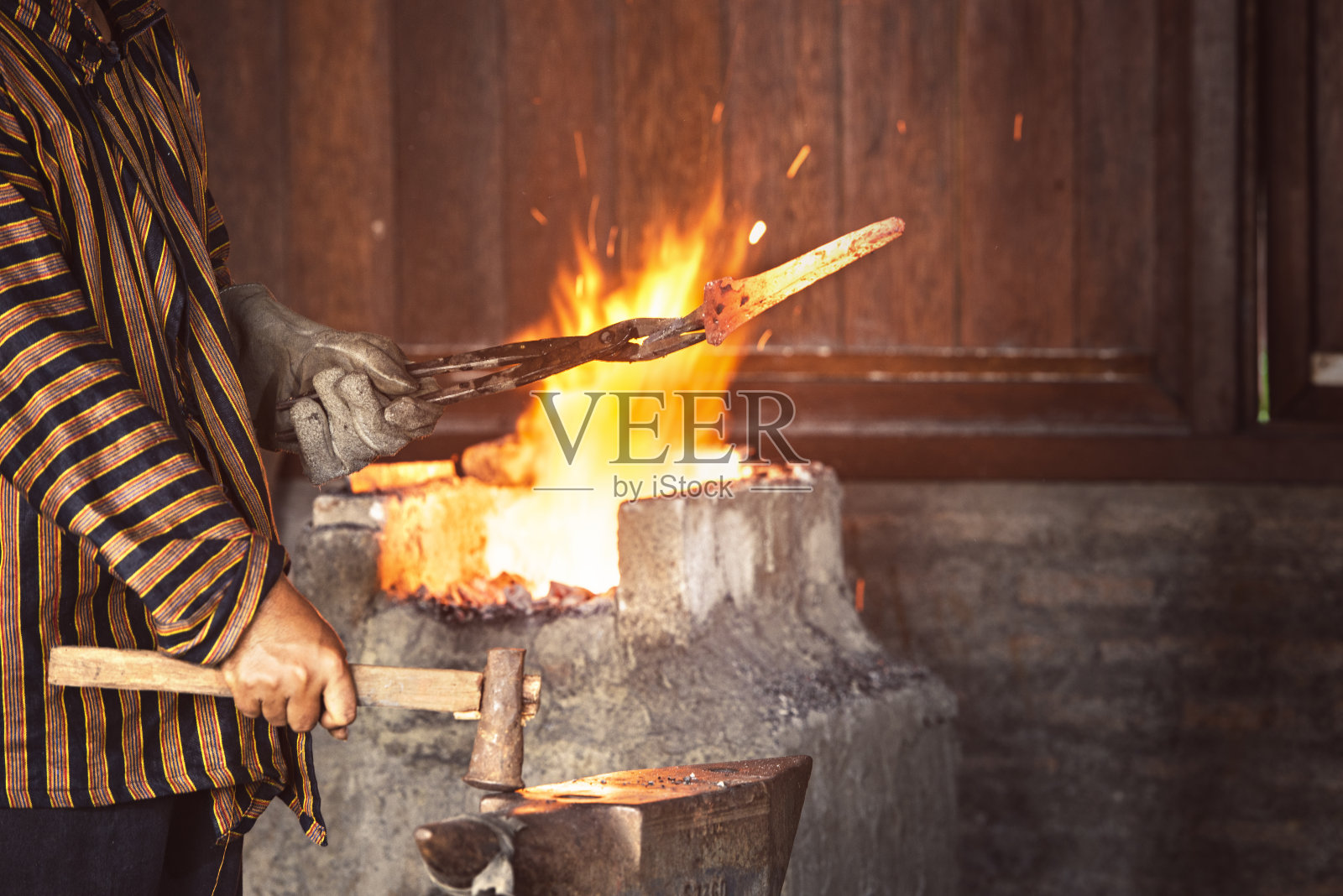 铁匠用铁锤锻造熔化的金属,使之成形照片摄影图片