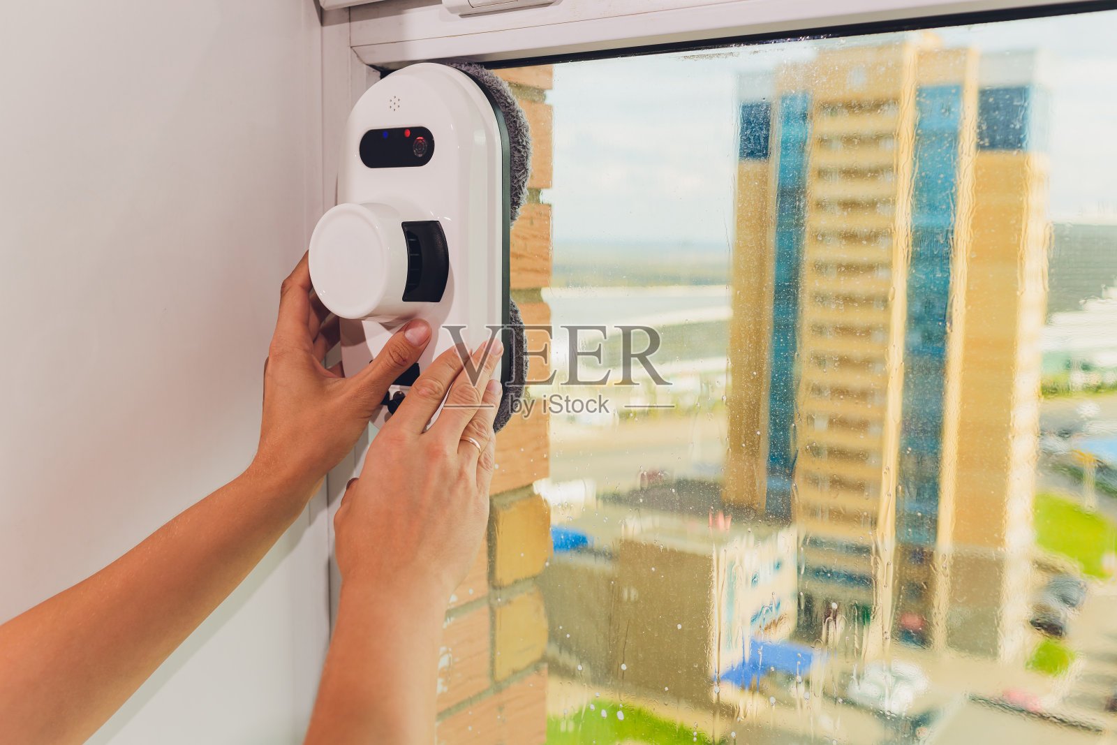 吸尘器机器人清洁高层建筑室外的窗户。照片摄影图片