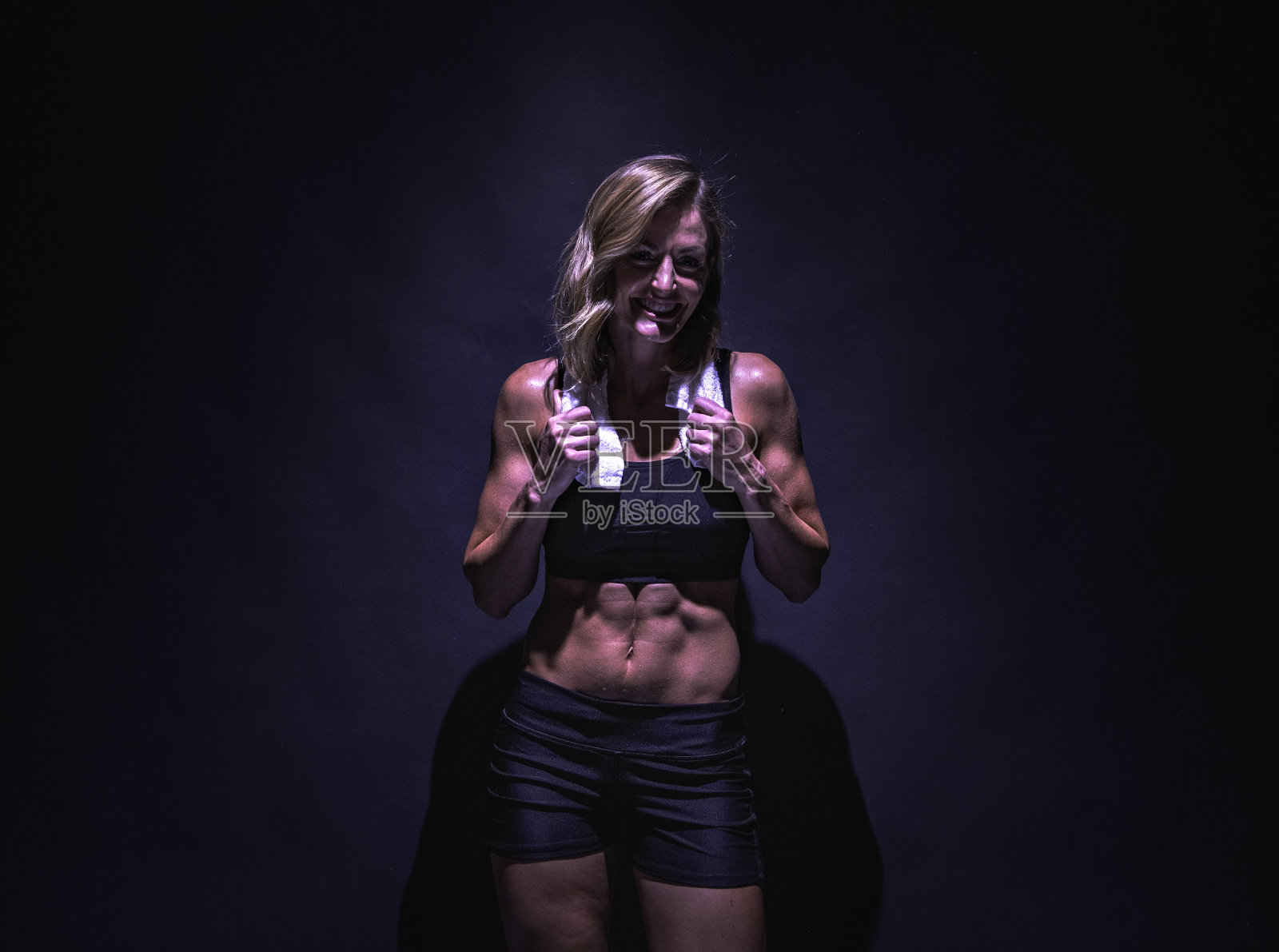 腰部以上/一个20-29岁的成年美丽的白人年轻女性/女性站在黑色背景穿着运动服装/运动胸罩/短裤/跑步短裤谁是微笑/快乐/愉快/黑色颜色照片摄影图片