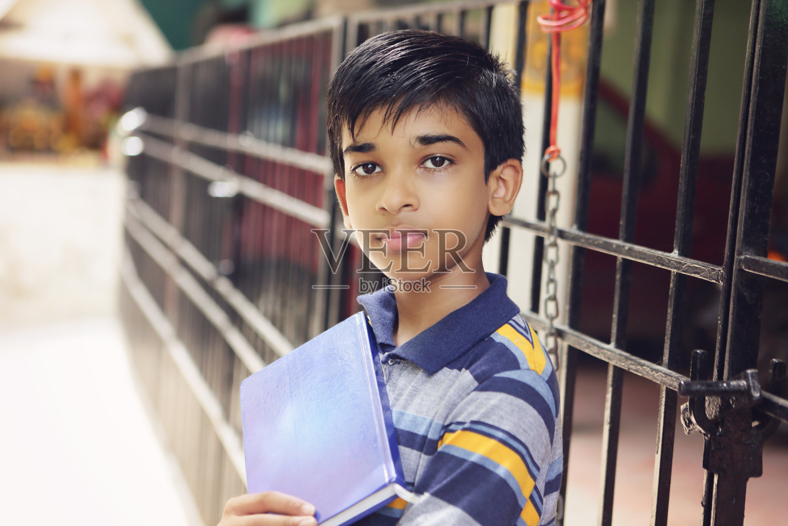 印度男孩对着相机摆姿势的肖像和课本照片摄影图片