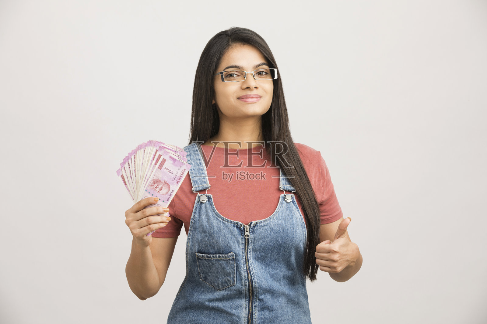 拿着存钱罐和卢比钞票的年轻女子照片摄影图片