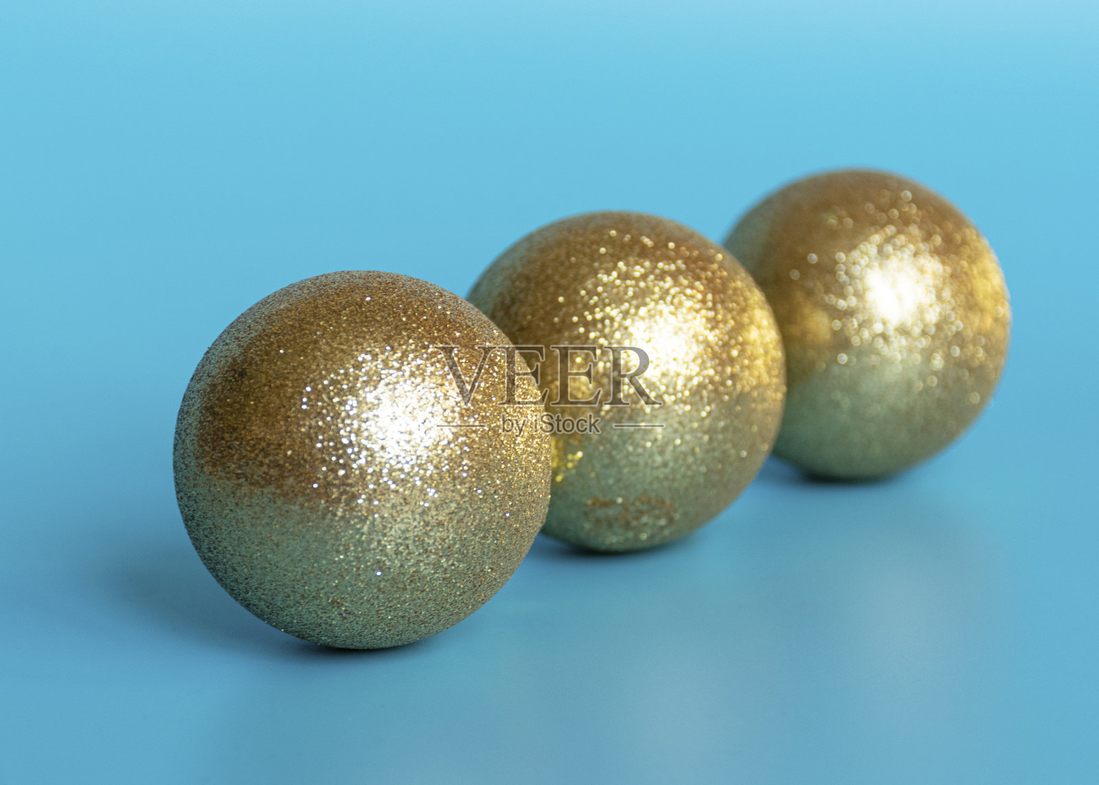 金色闪亮的彩球以蓝色的背景装饰新年和圣诞节的圣诞树。照片摄影图片