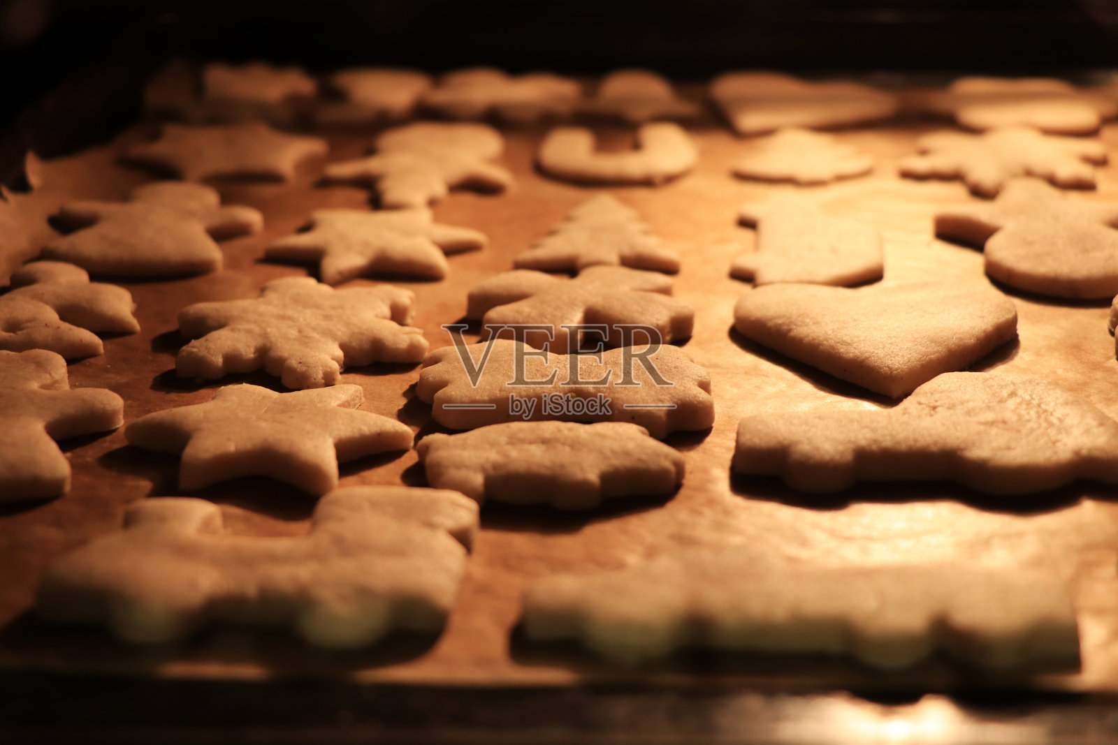 女人正在烤圣诞饼干,想找个合适的时间取出来。温暖的灯光和幸福的气氛意味着圣诞节的到来。给圣诞老人的礼物也是给小耶稣的照片摄影图片