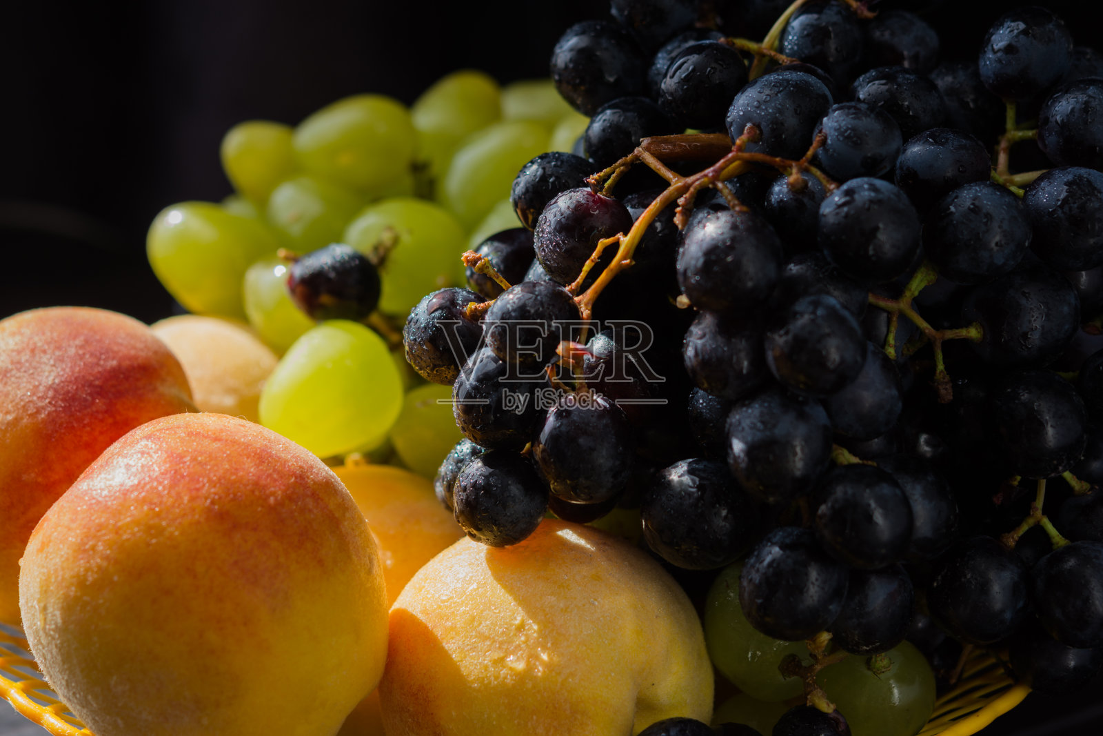 桌上的花瓶里装着葡萄和桃子照片摄影图片