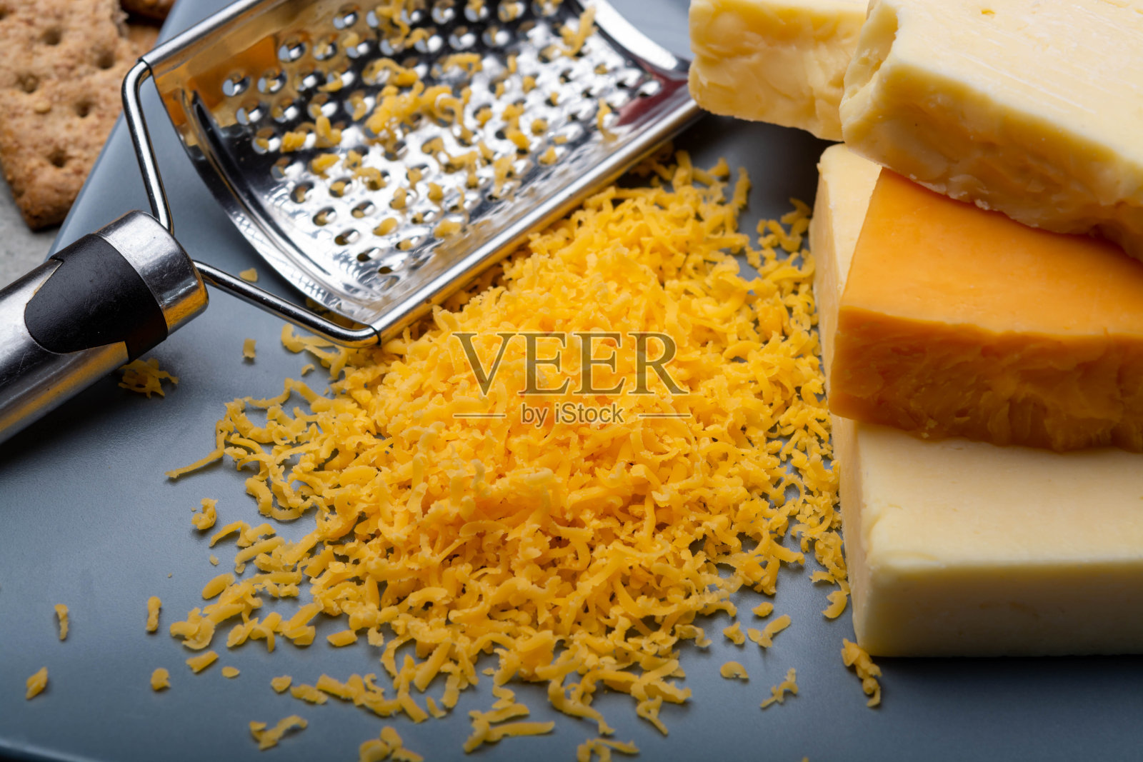 芝士精选,成熟的橙汁原味英国切达干酪块磨碎,盛在灰色盘子里照片摄影图片