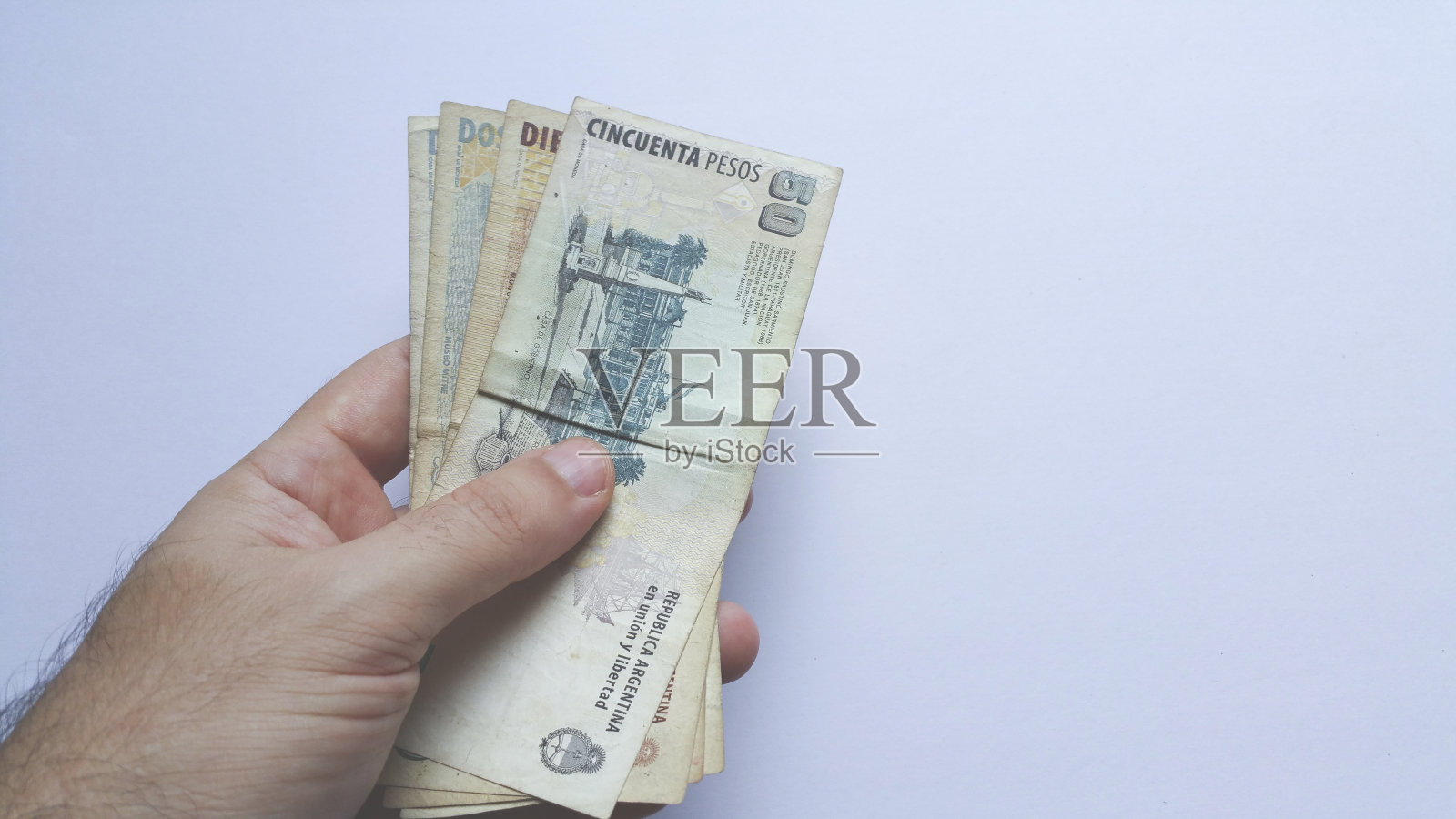 手里拿着白色背景的阿根廷钞票照片摄影图片