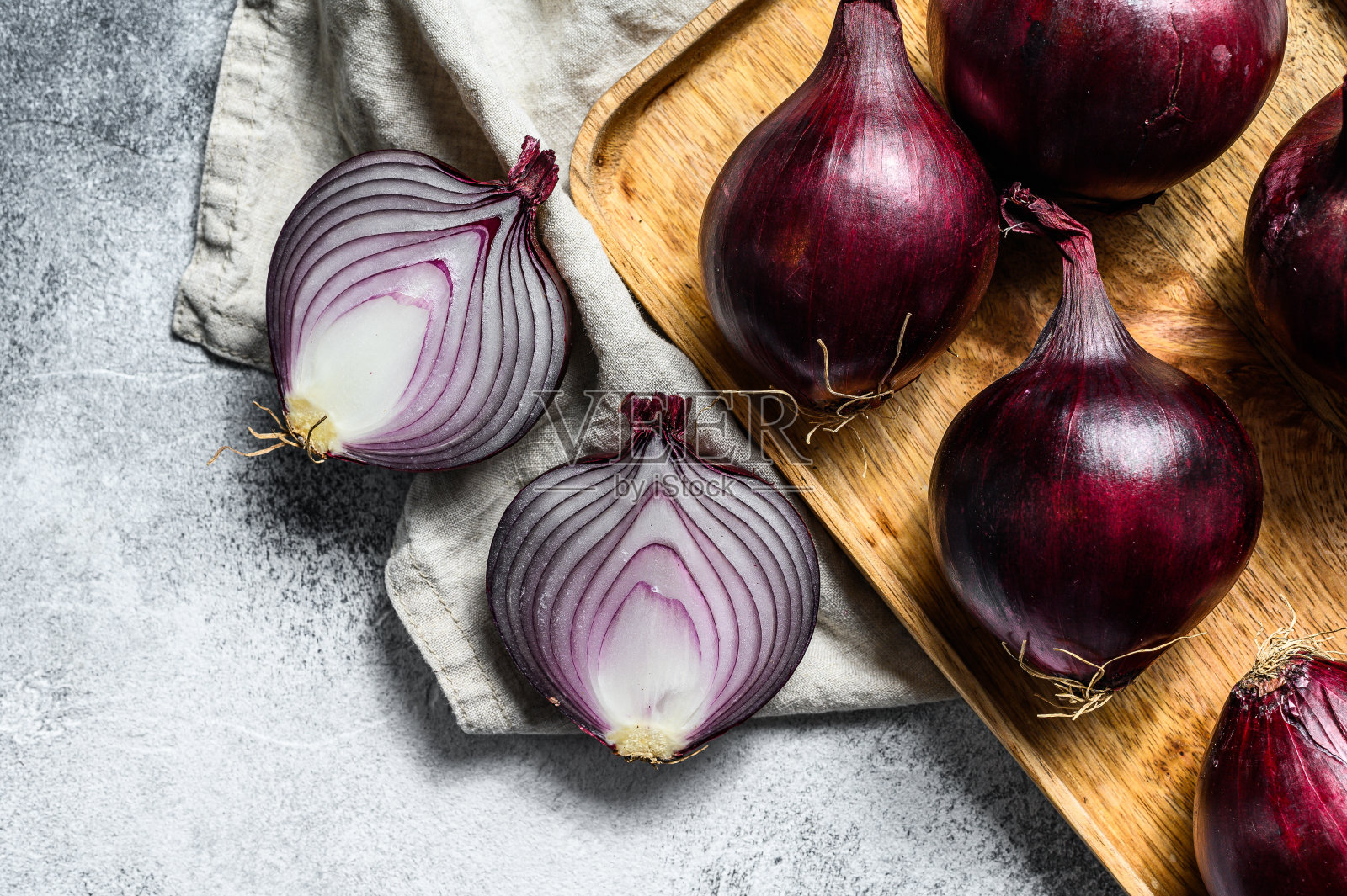 红洋葱放在木碗里,洋葱切成两半。农业生态蔬菜。灰色的背景。俯视图照片摄影图片