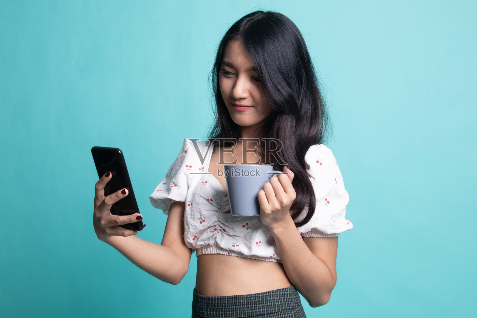 年轻的亚洲女人拿着手机和咖啡杯照片摄影图片