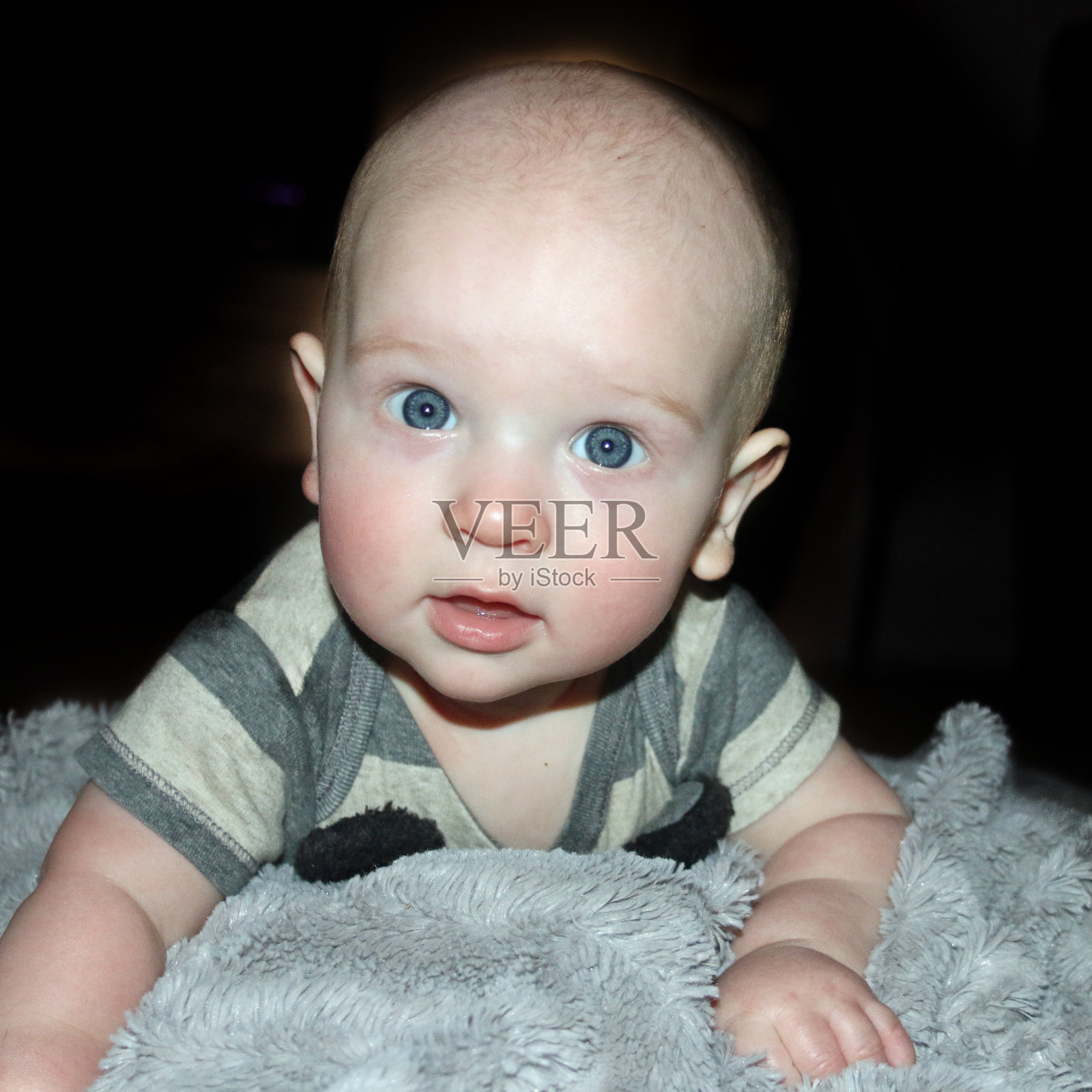 年轻的白人婴儿趴在地上抬起头照片摄影图片