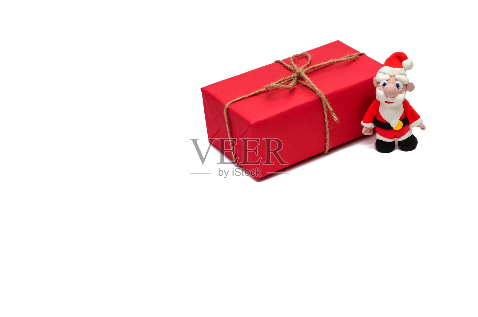白色背景上的圣诞老人小雕像和红色圣诞礼盒。圣诞节和新年假期概念。特写镜头照片摄影图片