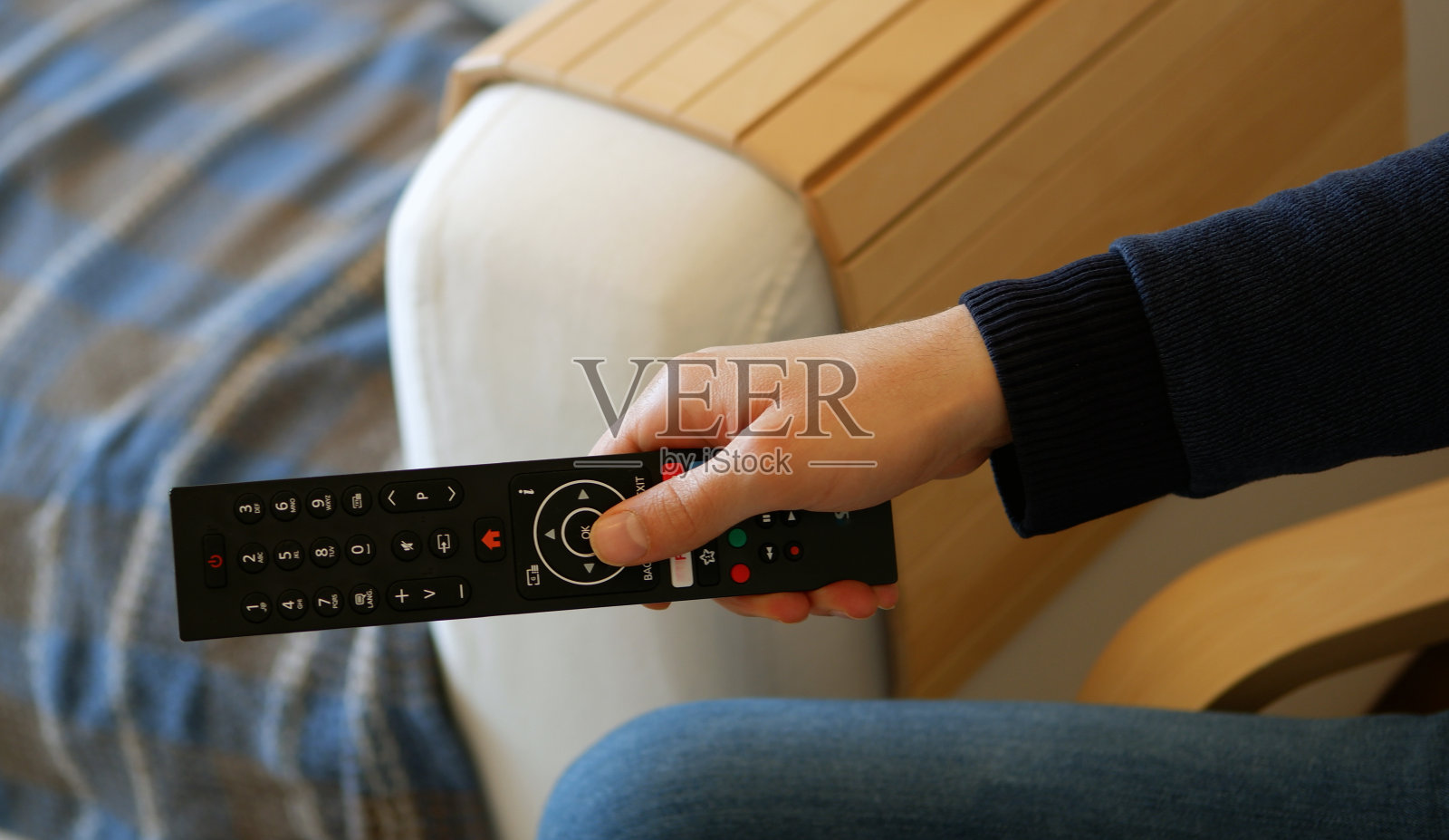 年轻人坐在椅子上,一边换电视频道照片摄影图片