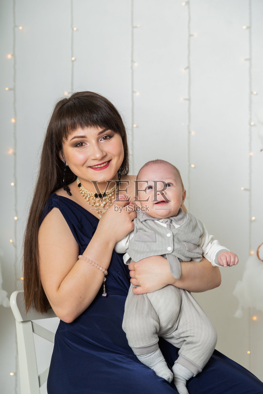 快乐的母亲穿着晚礼服和一个孩子在照相馆照片摄影图片